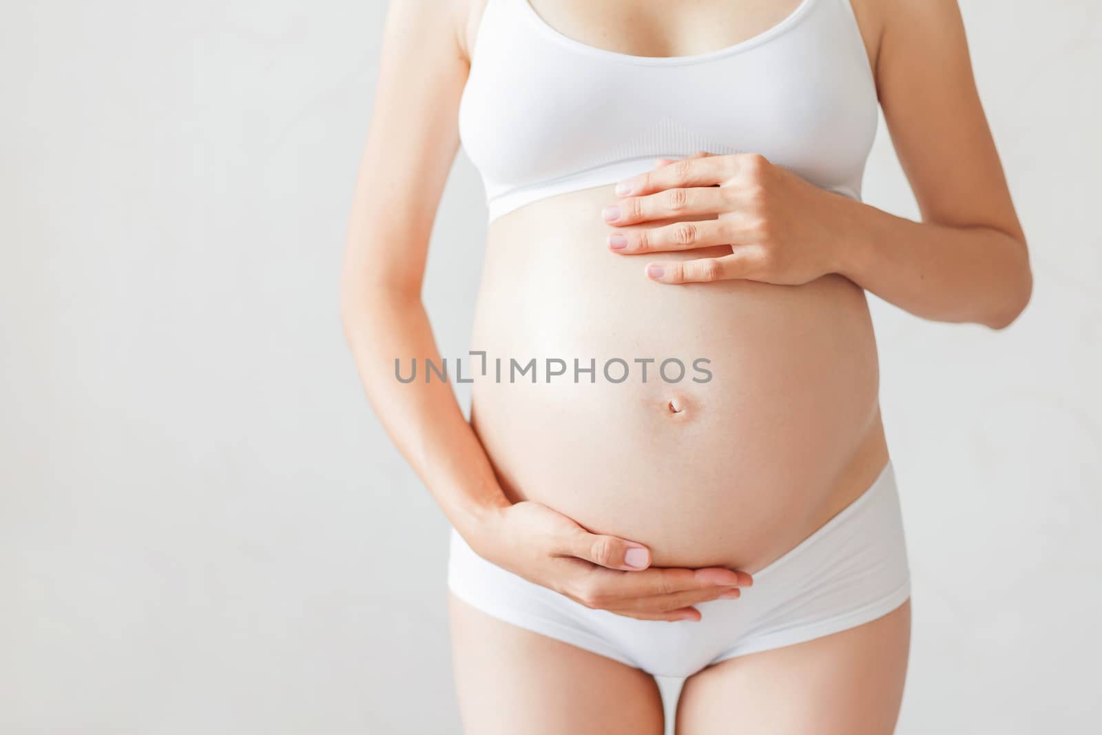 Pregnant woman in white underwear. Young woman expecting a baby.