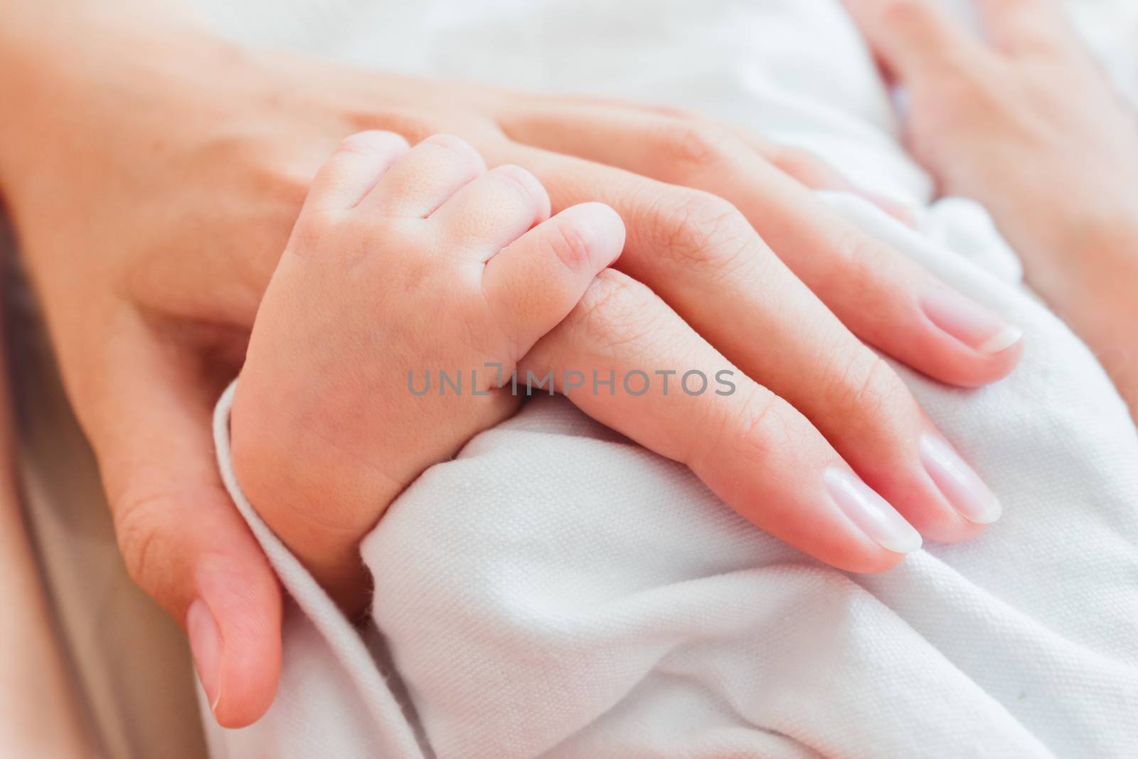 Newborn baby holding his mother finger. Hands of tiny baby and adult woman. Moment of tenderness.