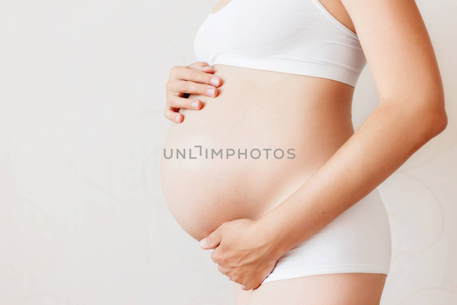 Pregnant woman in white underwear. Young woman expecting a baby.