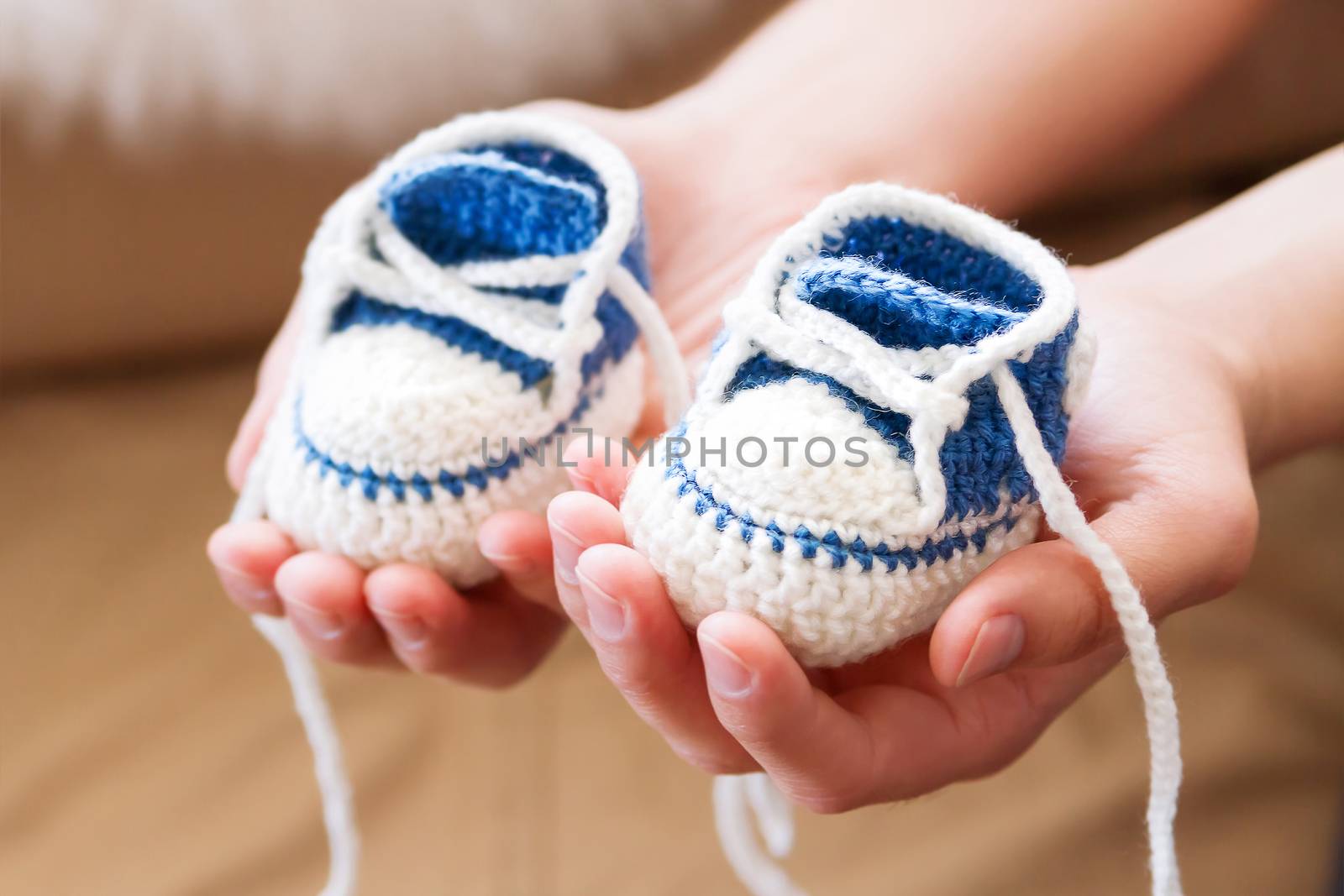 Little baby shoes. Handknitted first sneakers for boy or girl. Crochet handmade bootees in daddy's hands. Newly father presents knitted shoes.