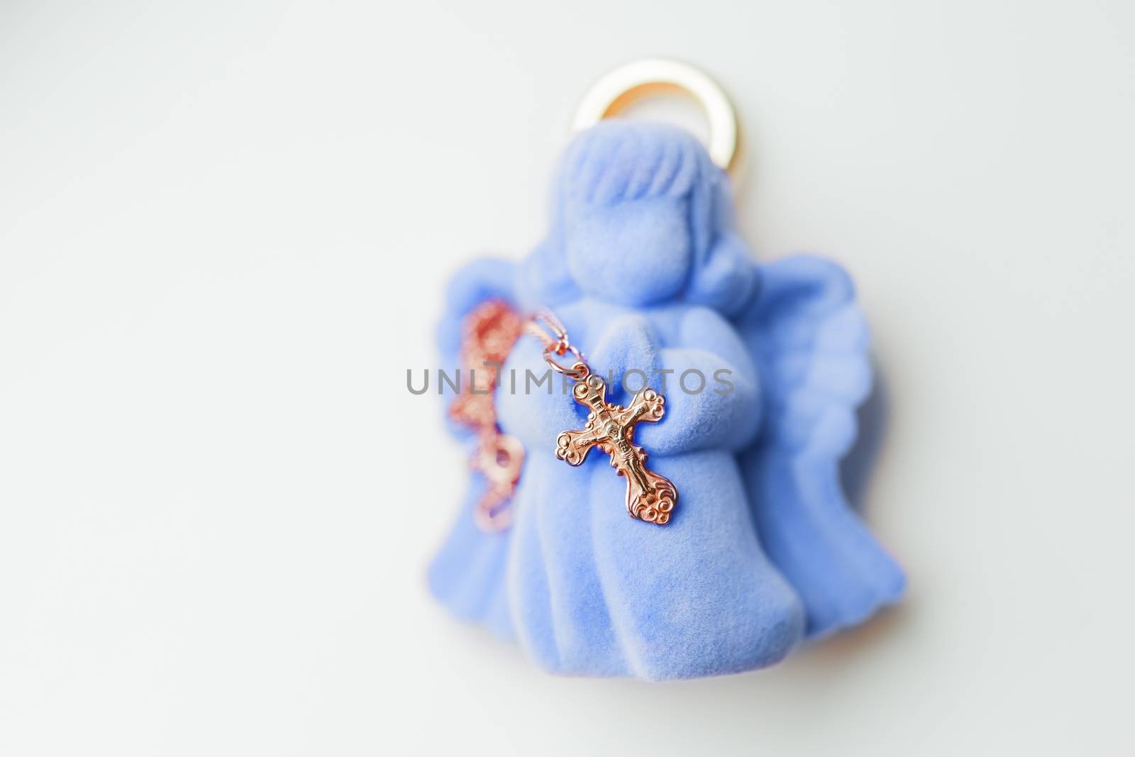 Golden cross for christening on pink gift box in shape of praying angel. Elegant religious accessory for little baby boy. Russian Orthodox church ceremony details.