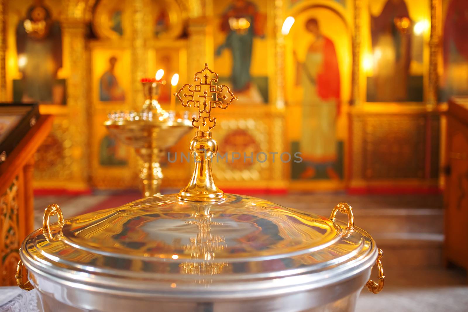 The font for the baptism of children in the Orthodox Church. Symbolic Orthodox gold cross on the cover font.