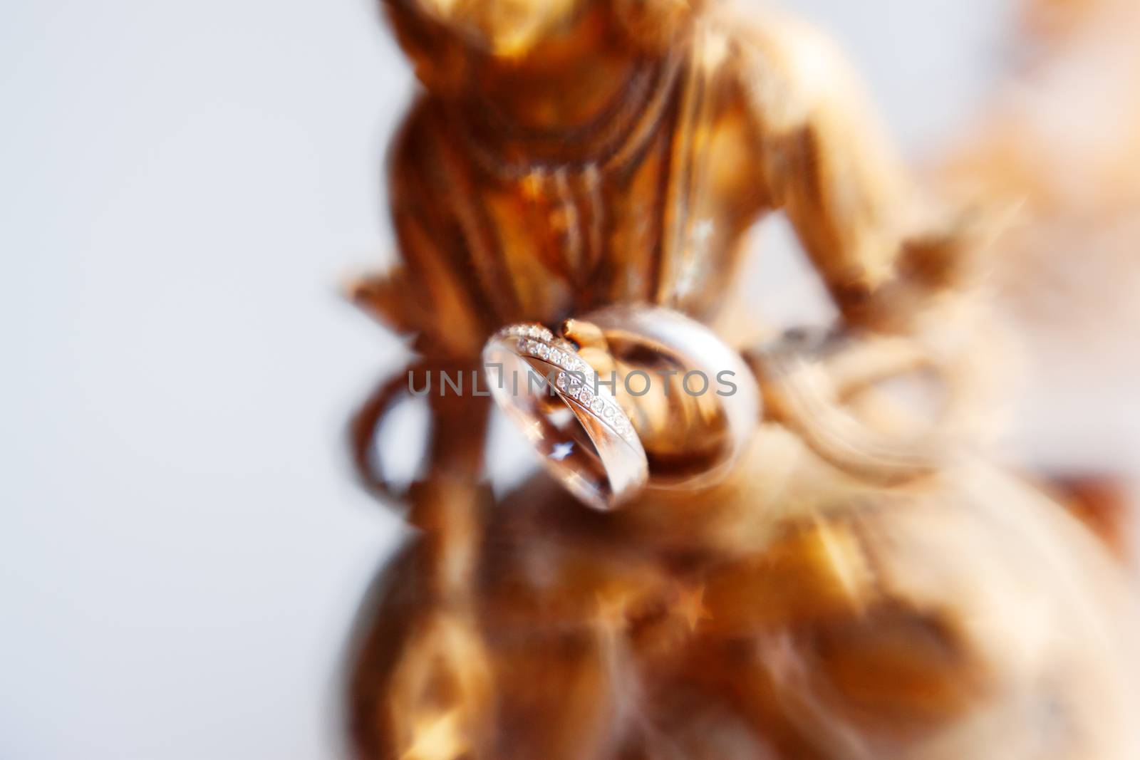 Pair of wedding rings with diamonds on unknown goddess statue. Old rusty metal sculpture captured with Lens Baby Sweet 35mm.
