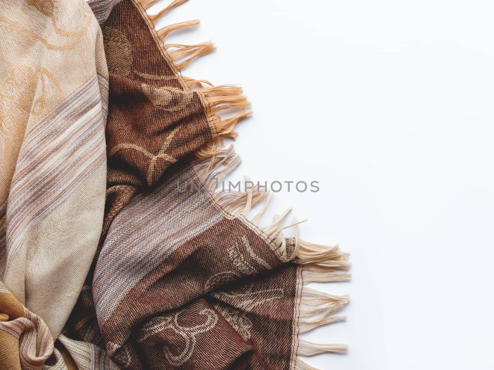 Beige and brown scarf on white background. Folded warm accessory with copy space.