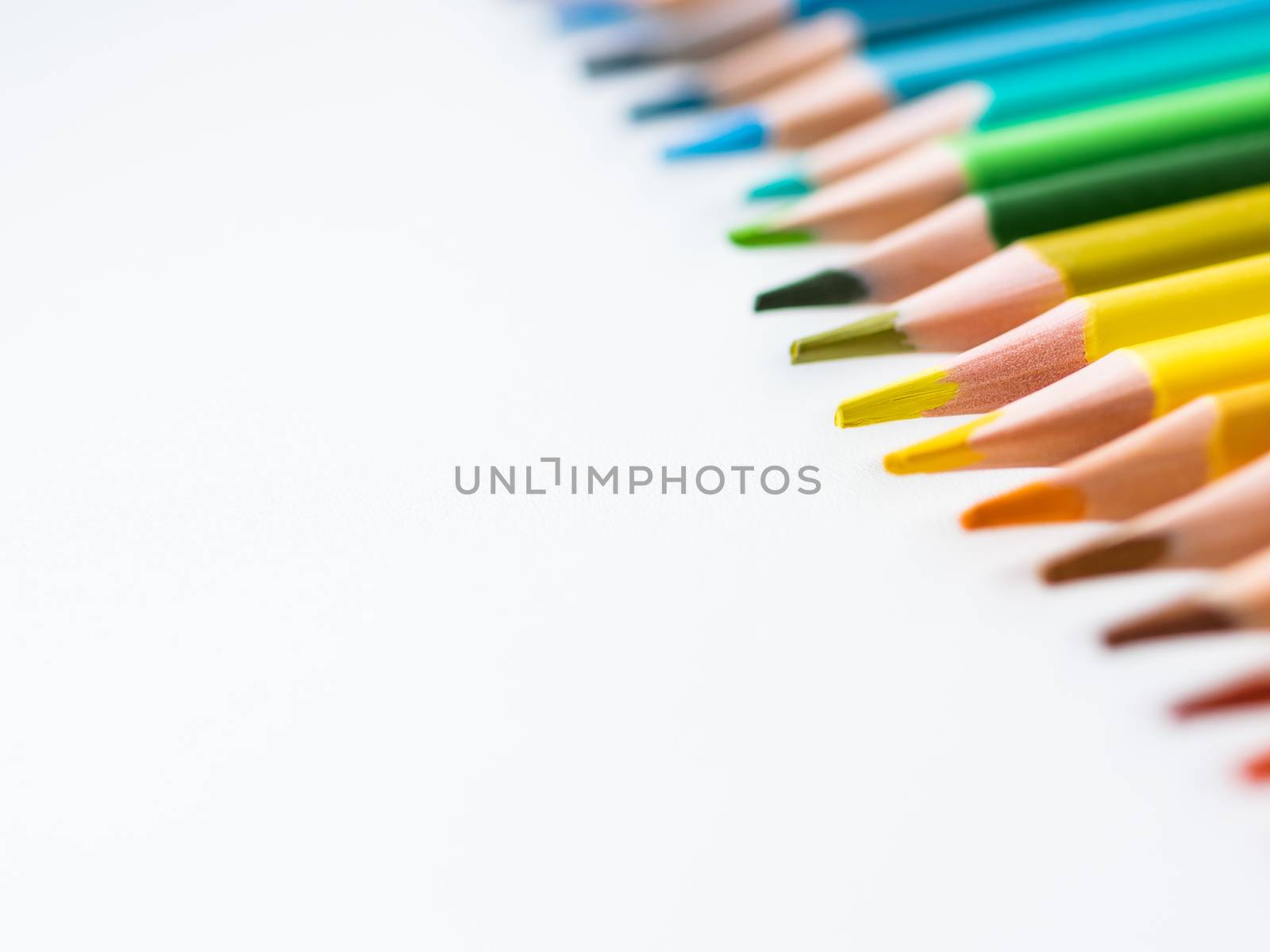 Row of colorful watercolor pencils on white background. School supplies. Kid's stationery with copy space. Back to school backdrop.