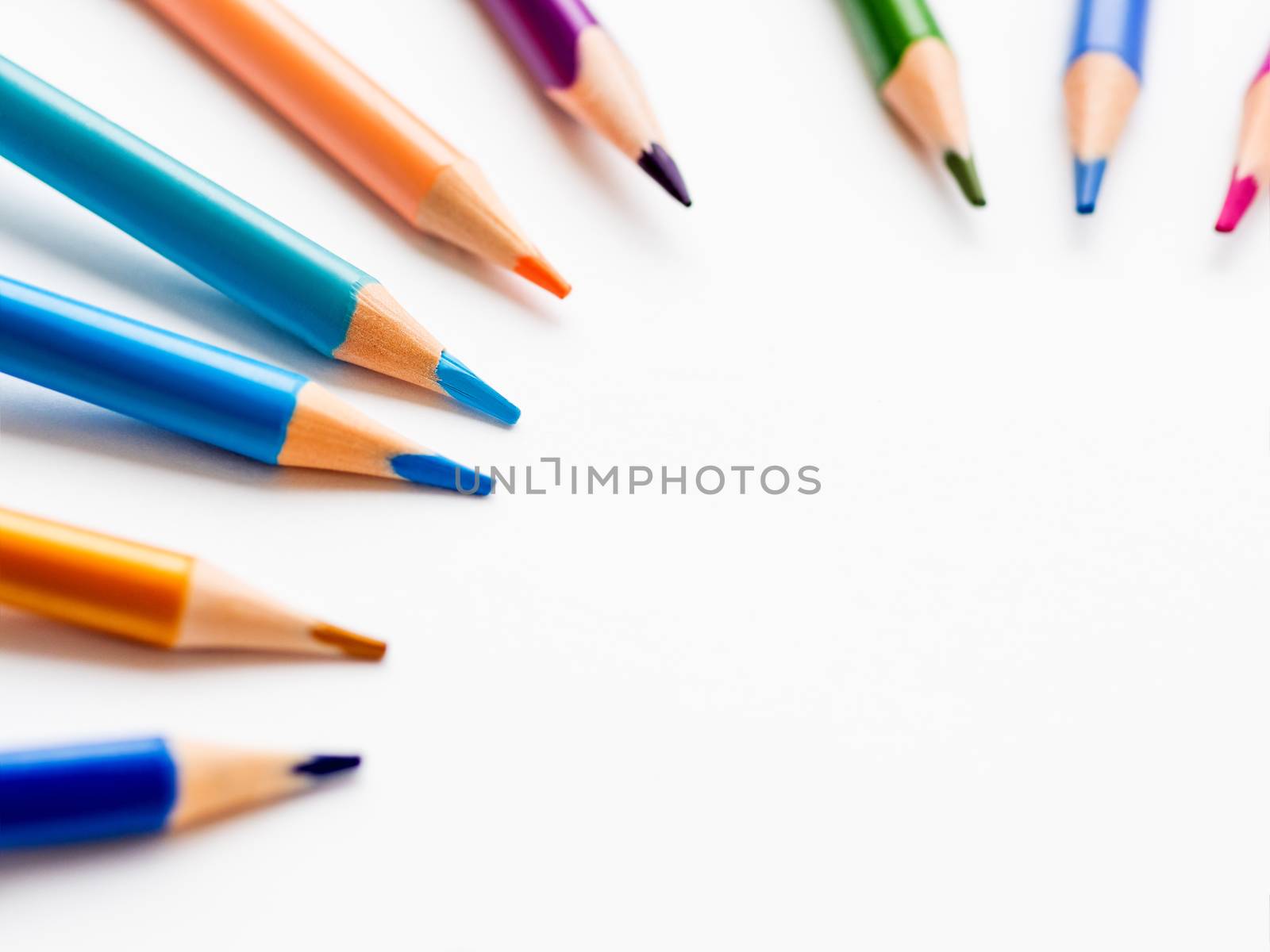 Colorful watercolor pencils on white background. School supplies with round copy space. Kid's stationery. Back to school circle backdrop.