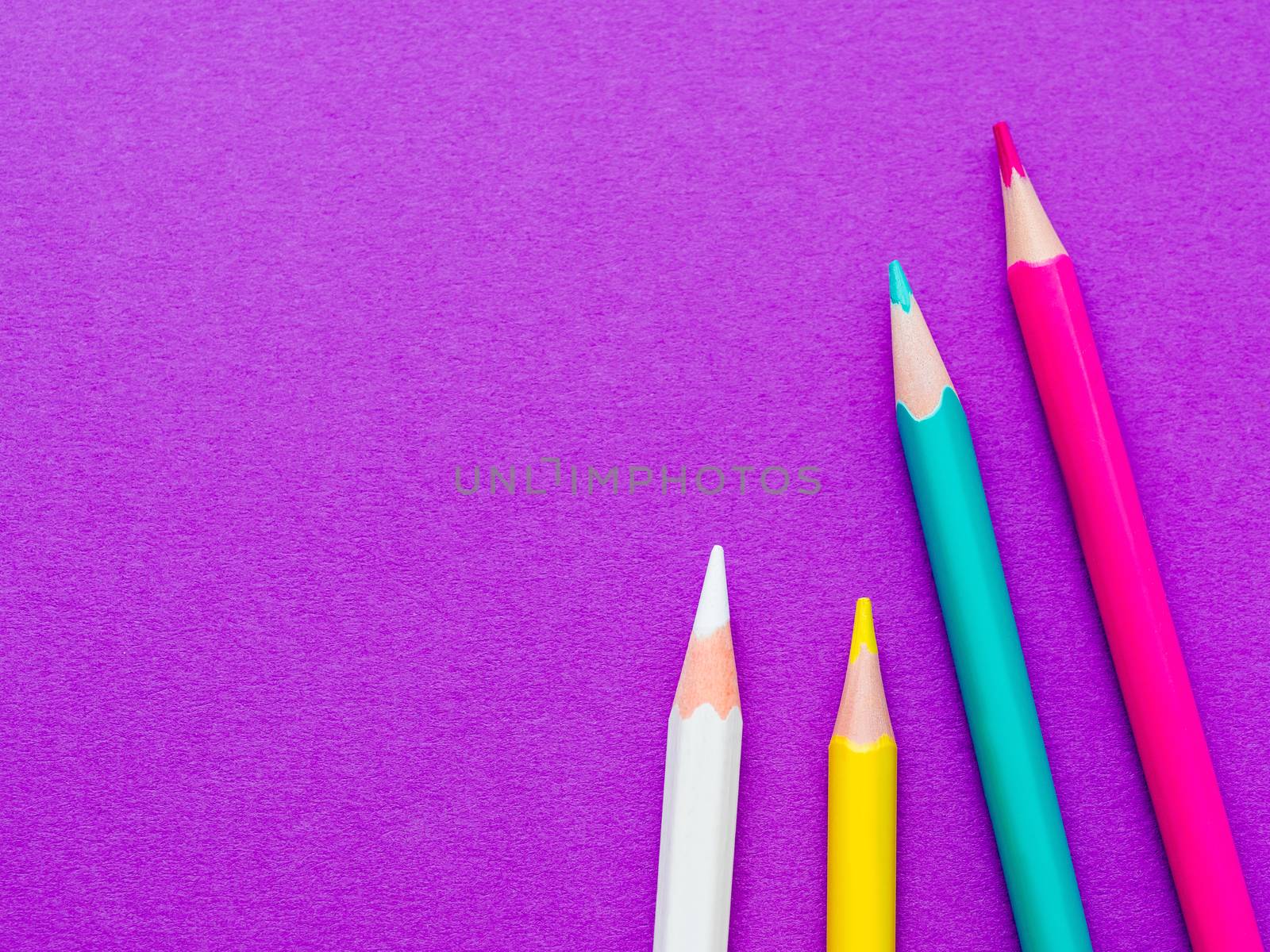 Row of colorful watercolor pencils on lilac background. School supplies on purple paper background. Kid's stationery. Back to school magenta backdrop.