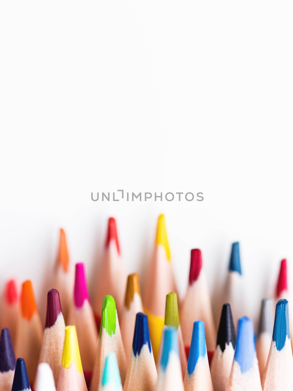 Vertical row of colorful watercolor pencils on white background. School supplies. Kid's stationery with copy space. Back to school backdrop.
