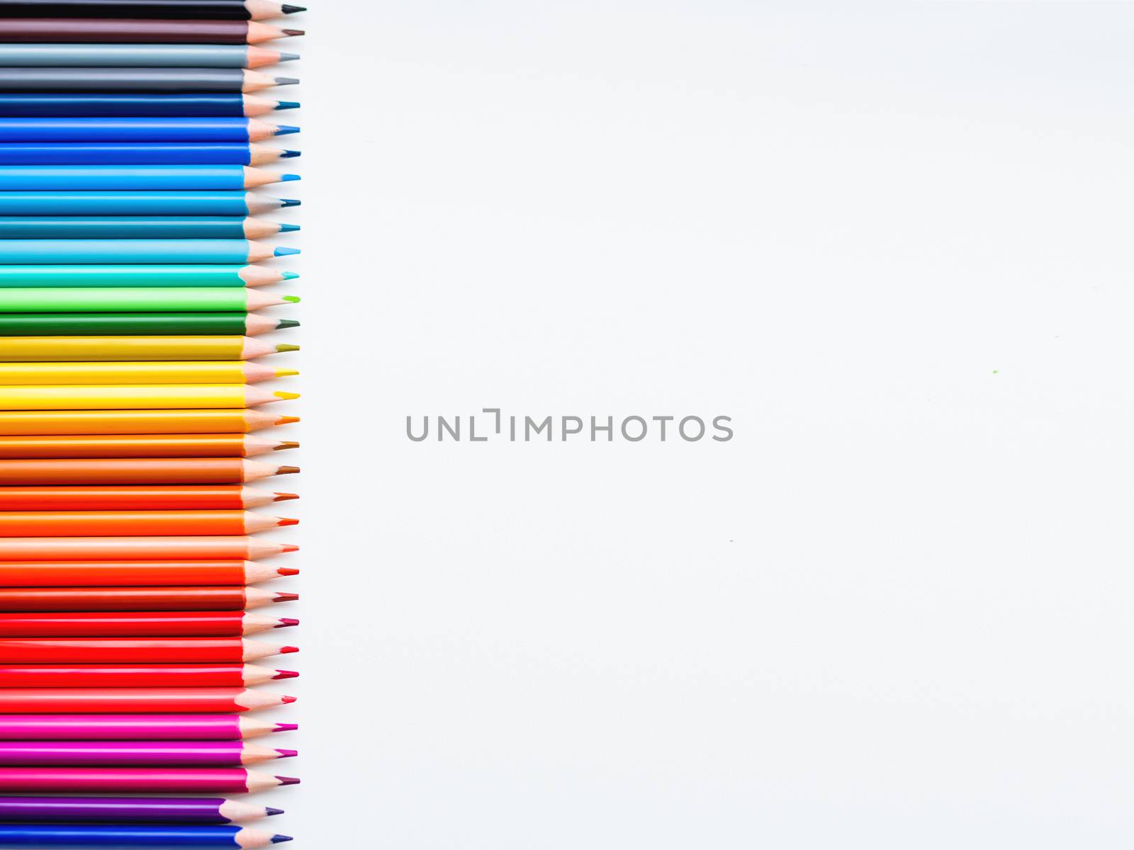 Horizontal row of colorful pencils on white background. School supplies in colores of rainbow. Kid's stationery with copy space. Back to school backdrop.