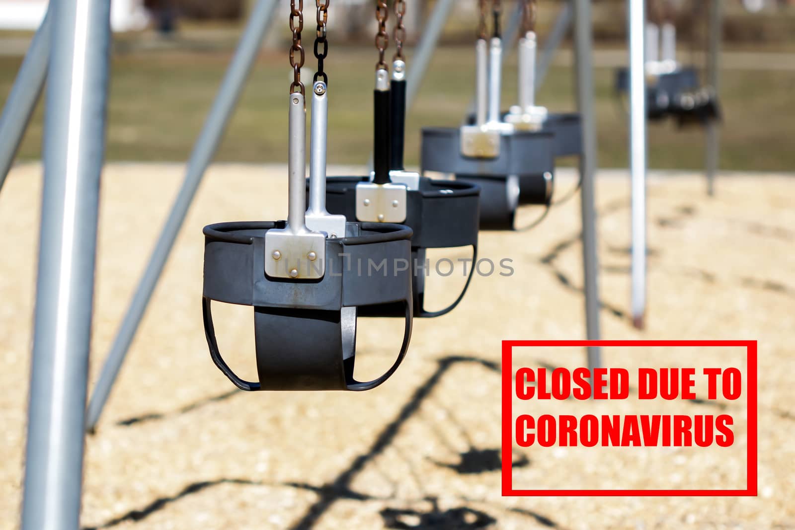 Empty swing seat on outside playground with red text closed due to coronavirus