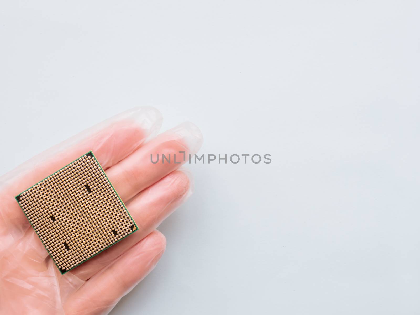 Hand in rubber glove with Central Computer Processor. CPU on light blue background. Technological detail of personal computer.