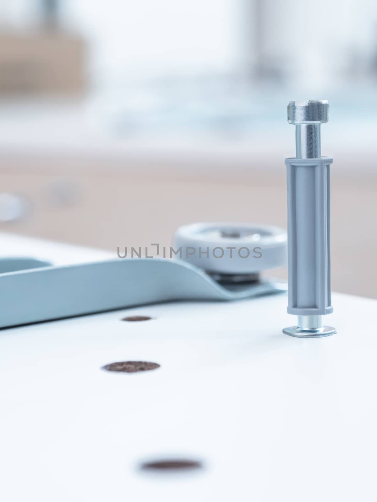 Self-assembly of furniture. The fasteners are installed in the drilled hole. DIY interior. Blue toned photo.