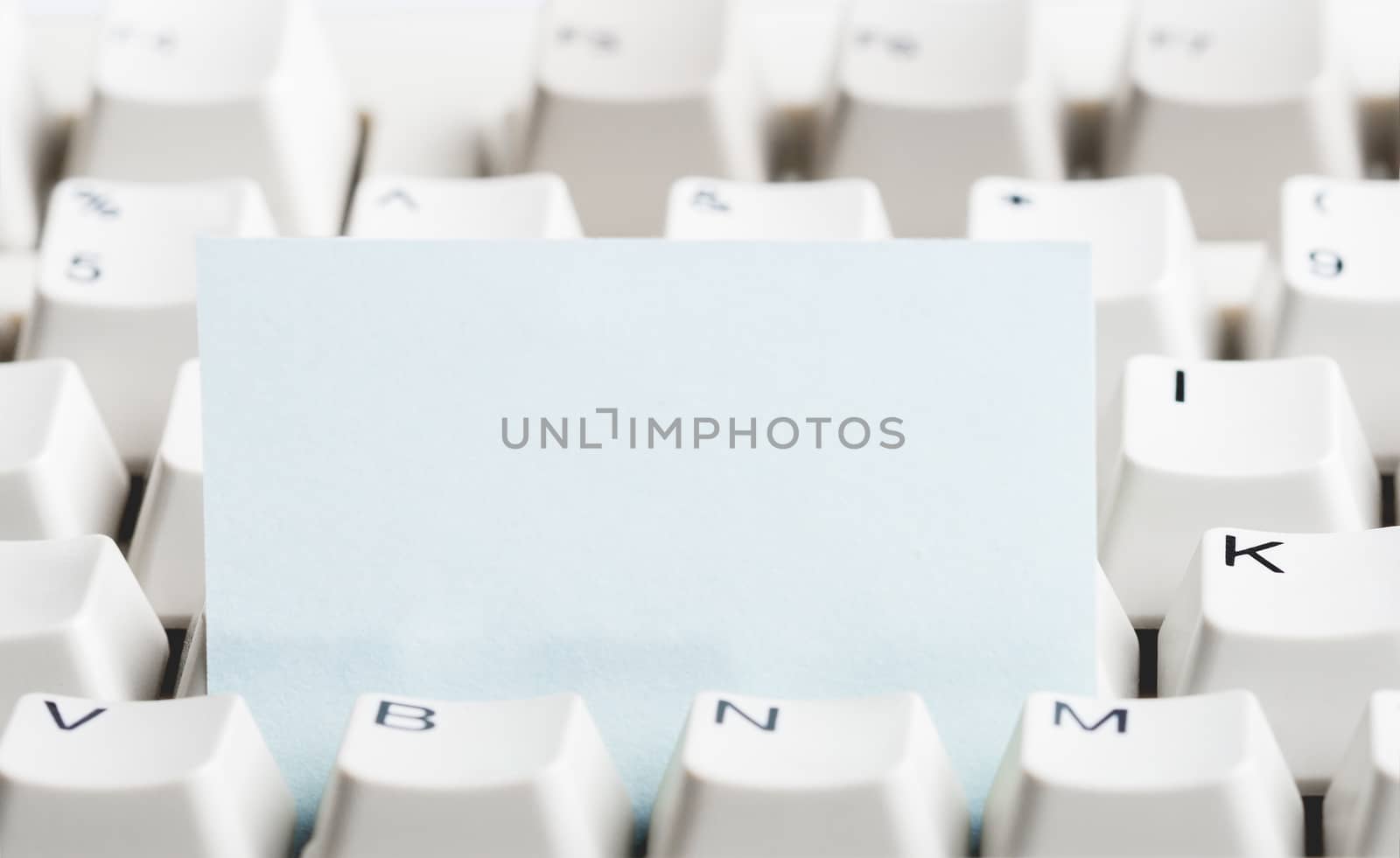 Clear paper stacked in white computer keyboard. May be used as mock up for note or message.