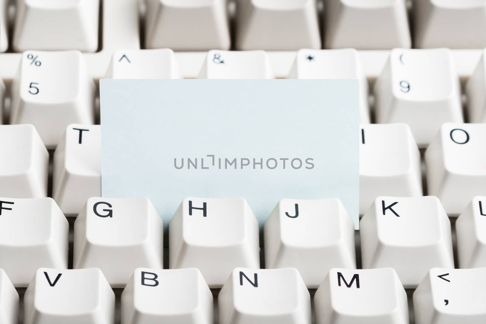 Clear paper stacked in white computer keyboard. May be used as mock up for note or message.