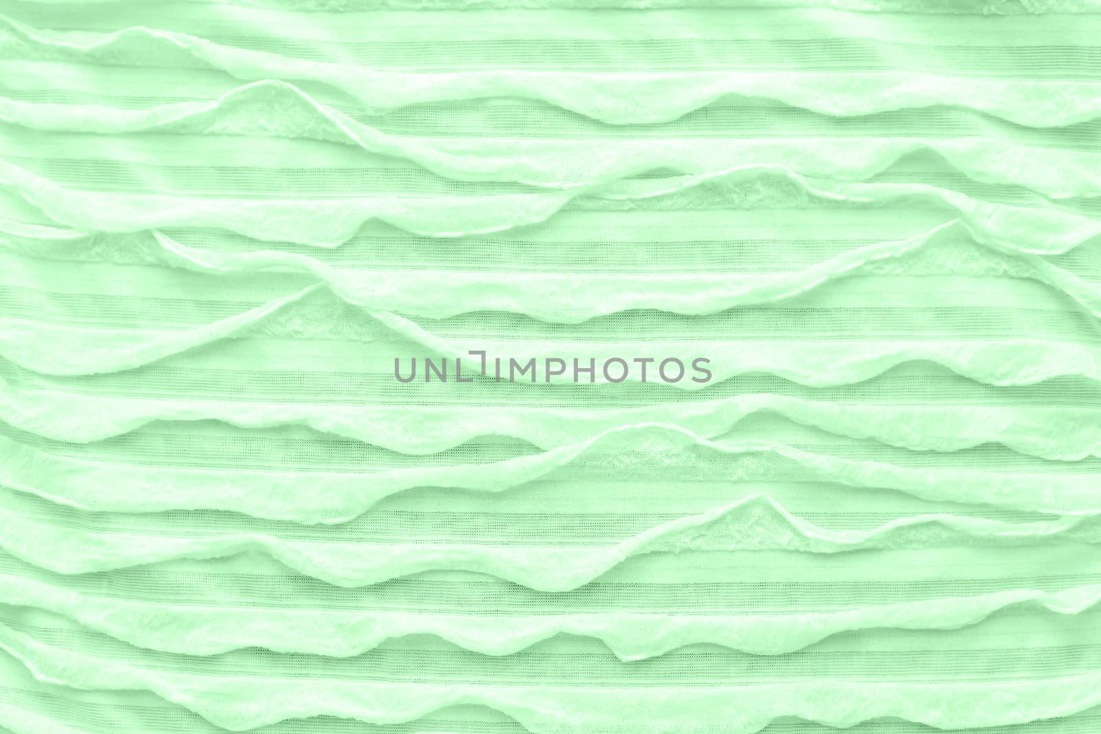 Abstract textile background. Neo mint colored fabric with ruche. Top view, flat lay.