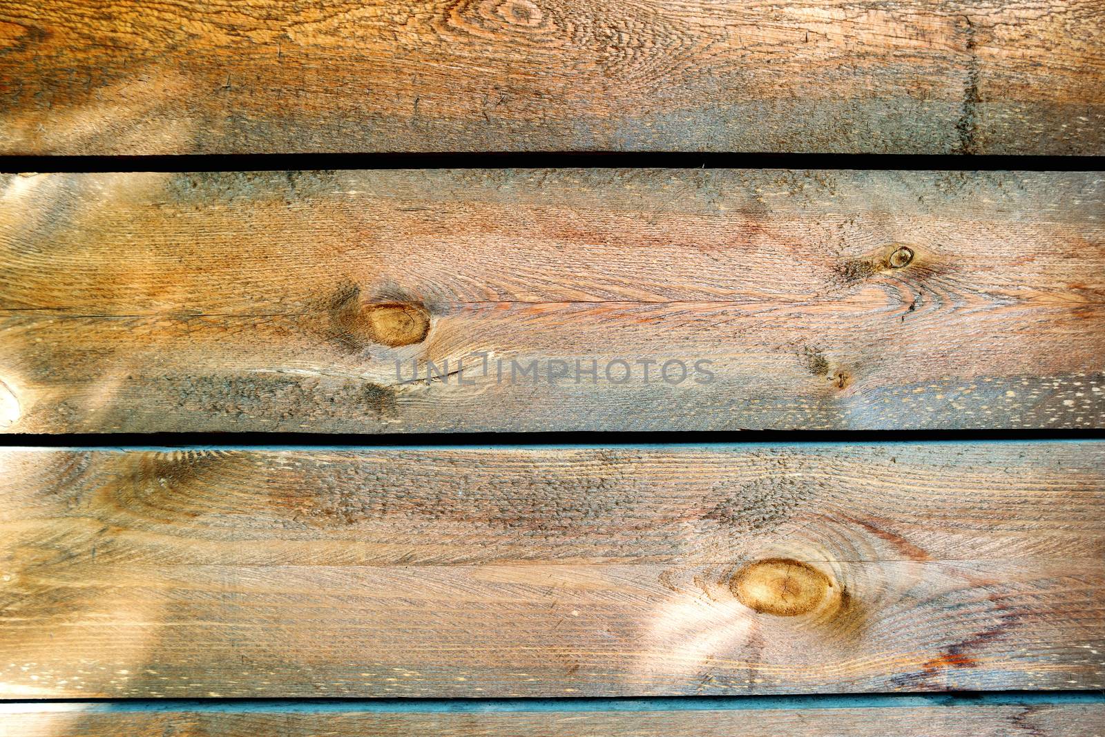 Wooden background of old fence with traces of branches. Shabby texture of colorful wooden boards.