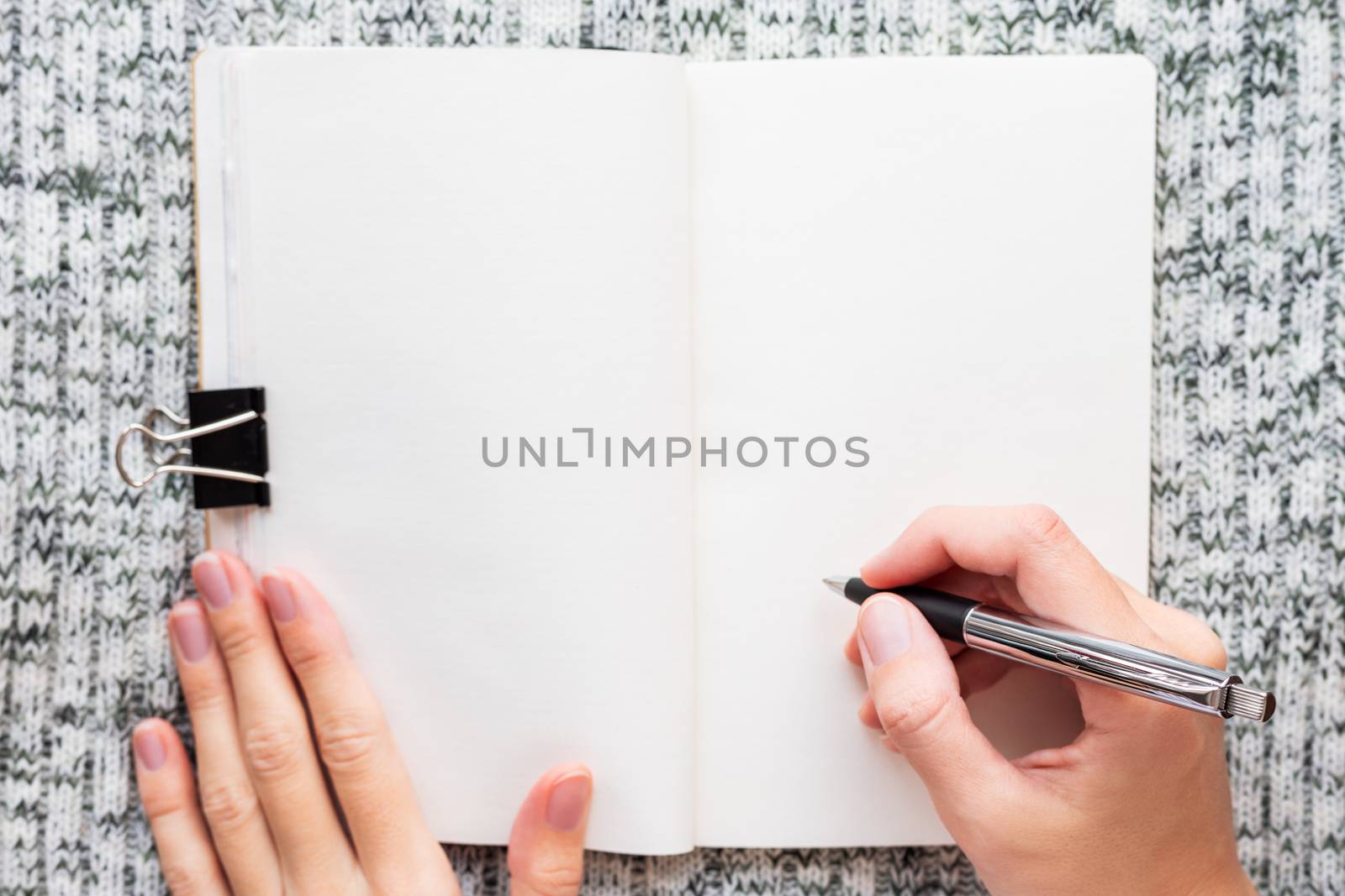 Sketchbook opened on clear page. Hands with pen. Woman is going to write or draw something.