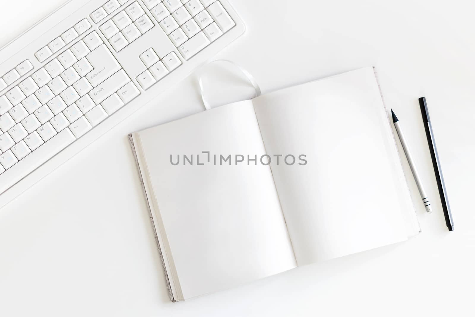 Top view on white table with keyboard, copybook with blank pages and pen with pencil. Flat lay.