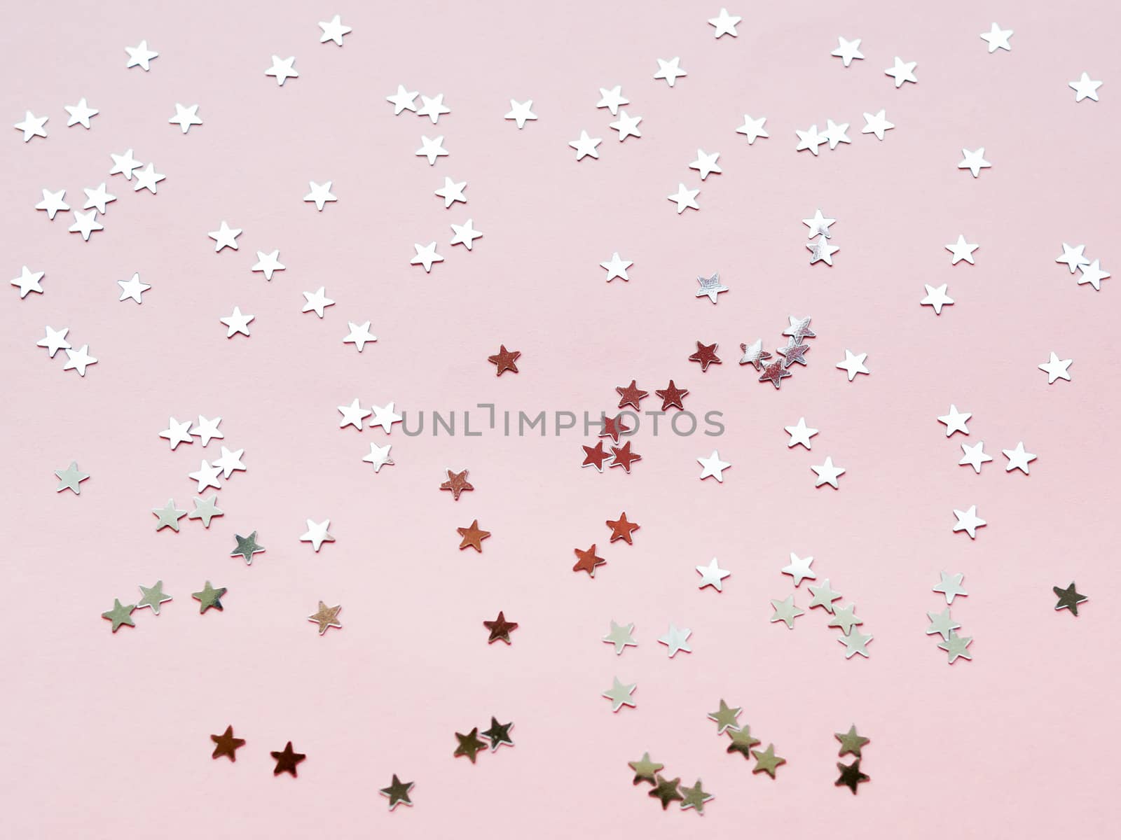 Holiday background with silver star confetti on pink background. Good backdrop for Christmas and New Year cards. Flat lay, top view.