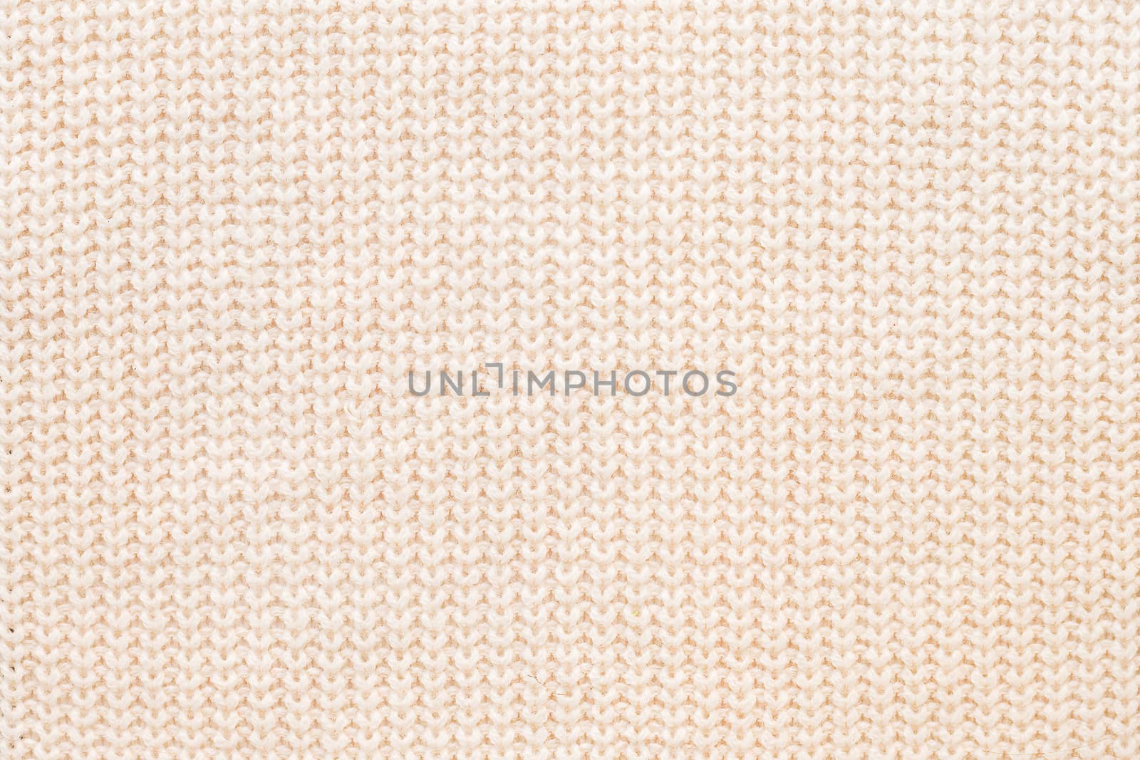 Abstract knitted background. Wool beige sweater texture. Close up picture of knitted pattern.