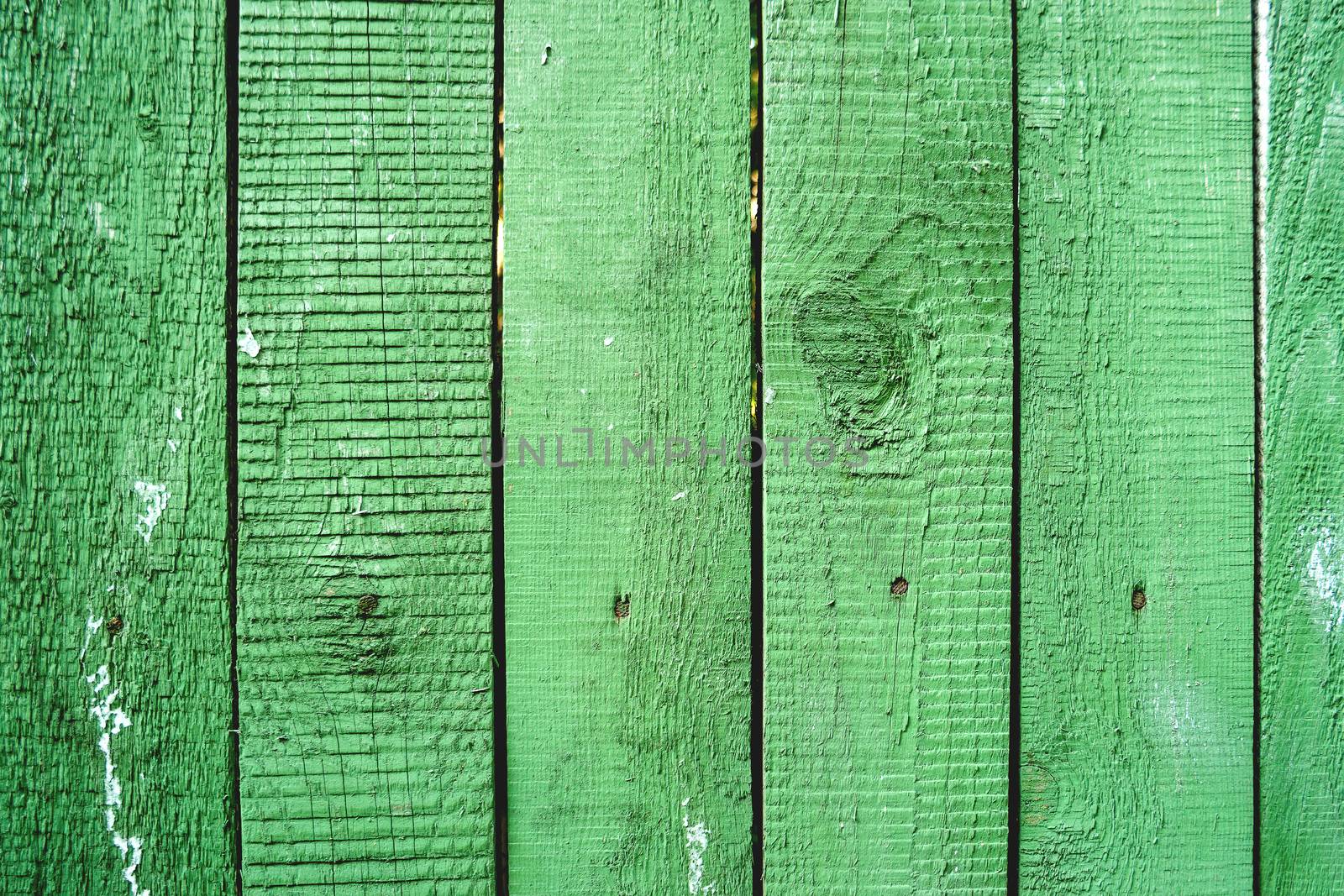 Wooden background of old fence with rusty nails. Shabby texture of green colored wooden boards.