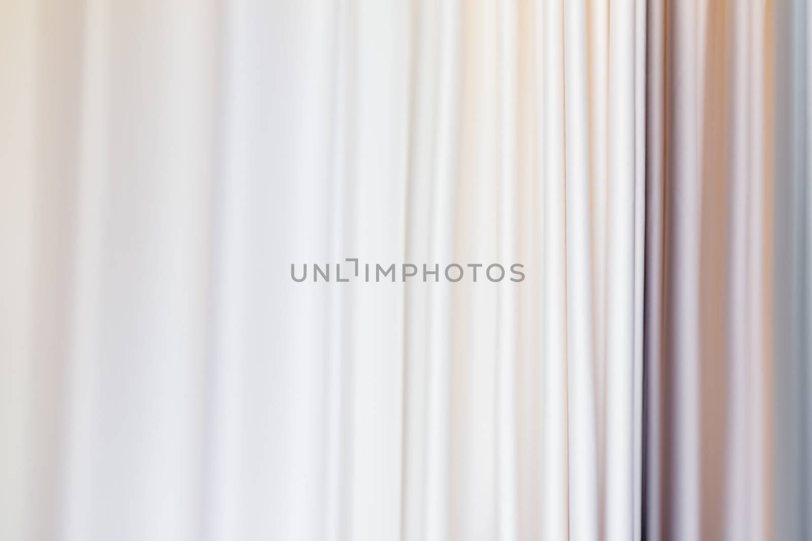 Pastel colored curtains on window. Textile folds of drapery.