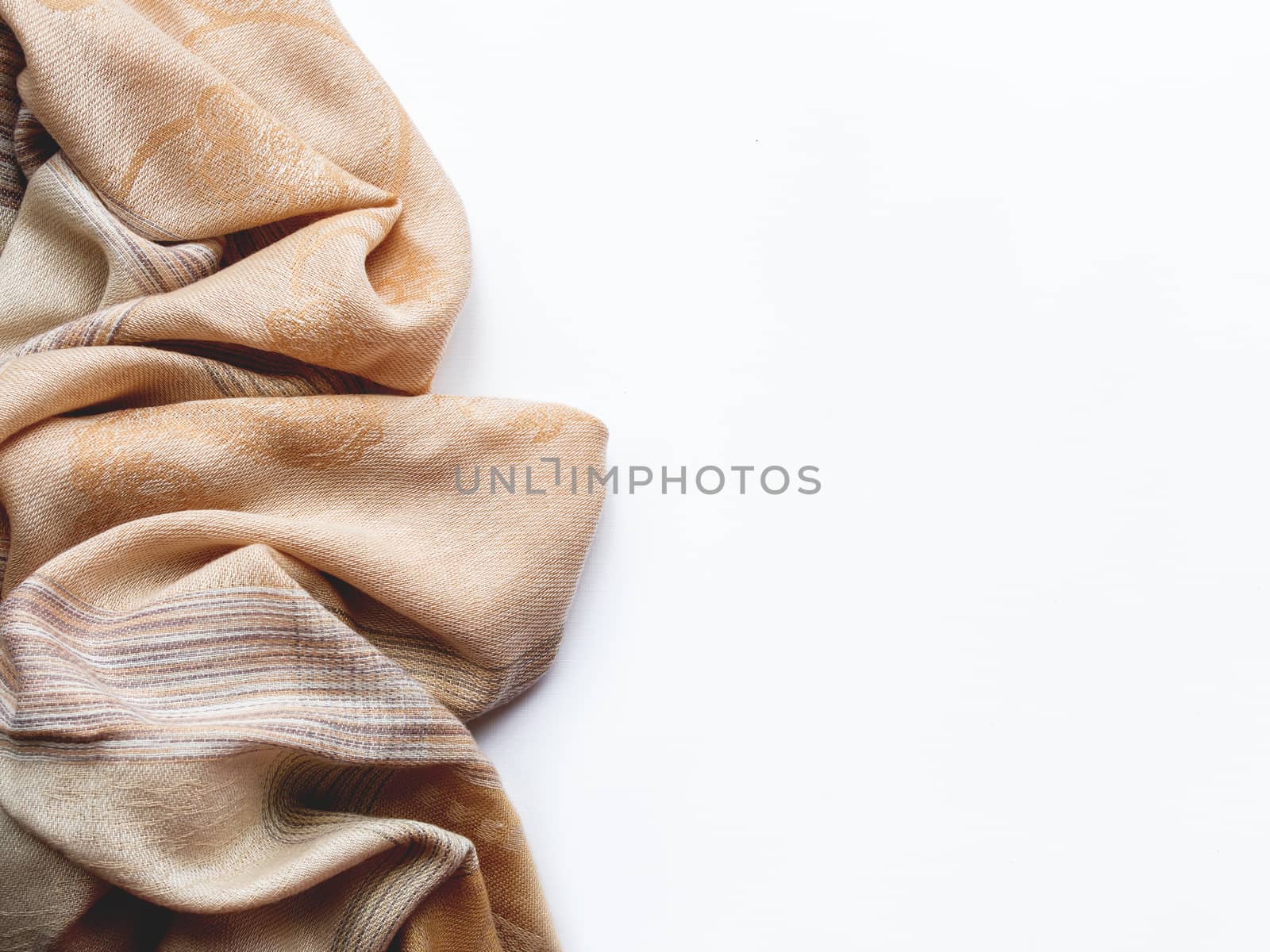 Beige and brown scarf on white background. Folded warm accessory with copy space.