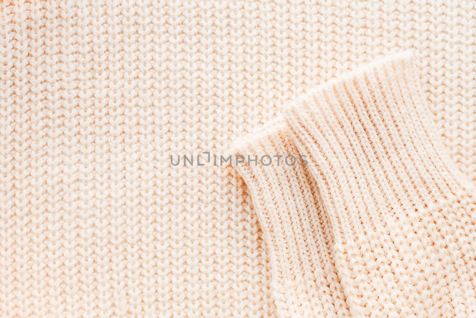 Abstract knitted background. Wool sweater with sleeves. Close up picture of knitted pattern.