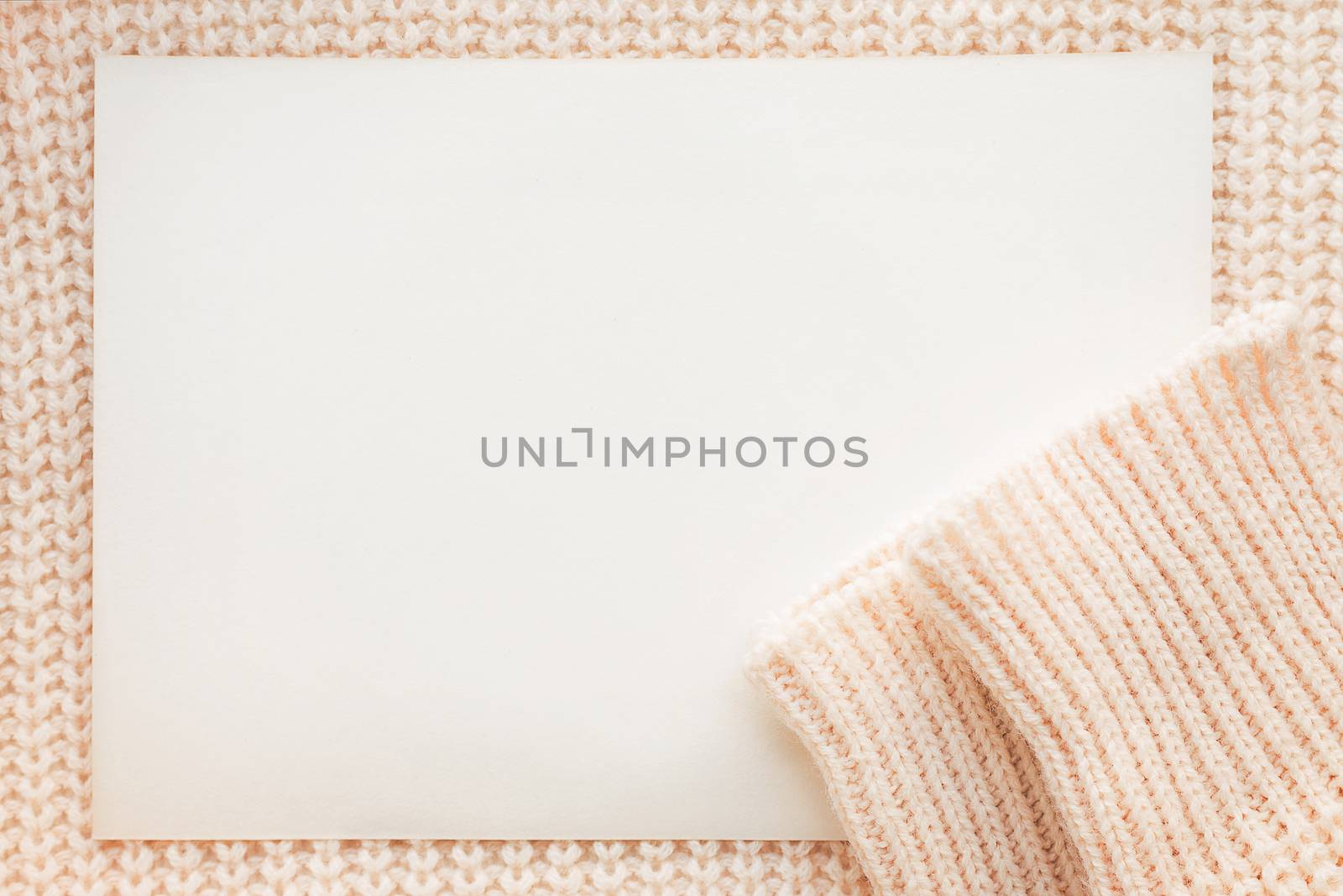 Abstract knitted background with clear paper. Wool sweater with sleeves. Close up picture of knitted pattern.