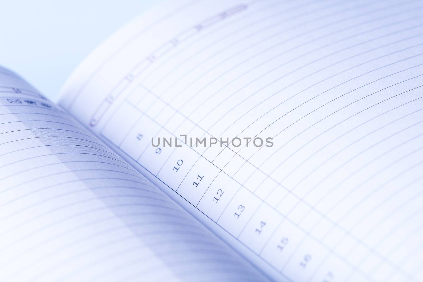 Clear pages of undated diary. Blue light falls on the numbered lines of daily planner. To do list.