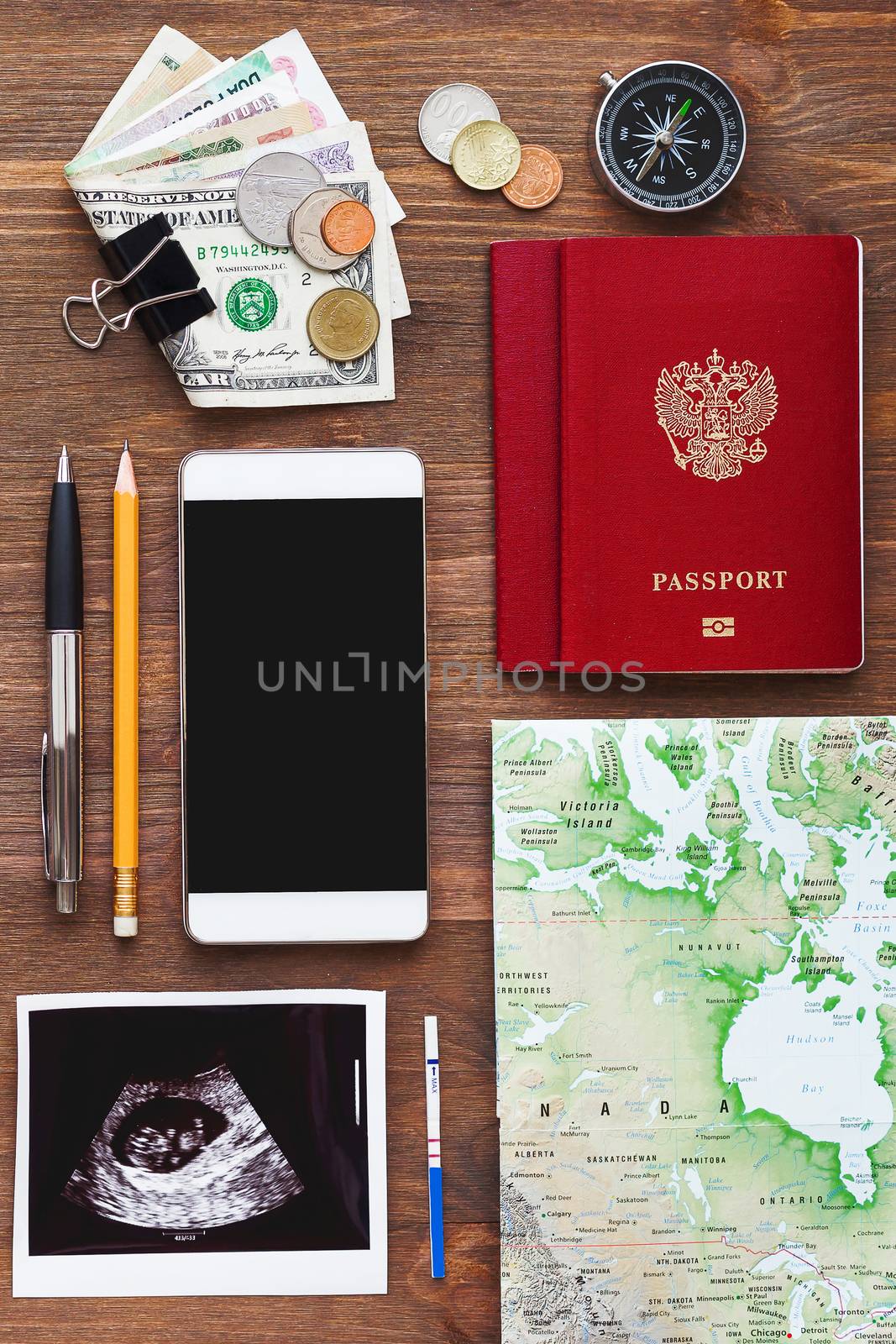 Travel while being pregnant background. Different things you need for journey - smartphone, passport, map, money. Ultrasound photo of baby and positive pregnancy test.