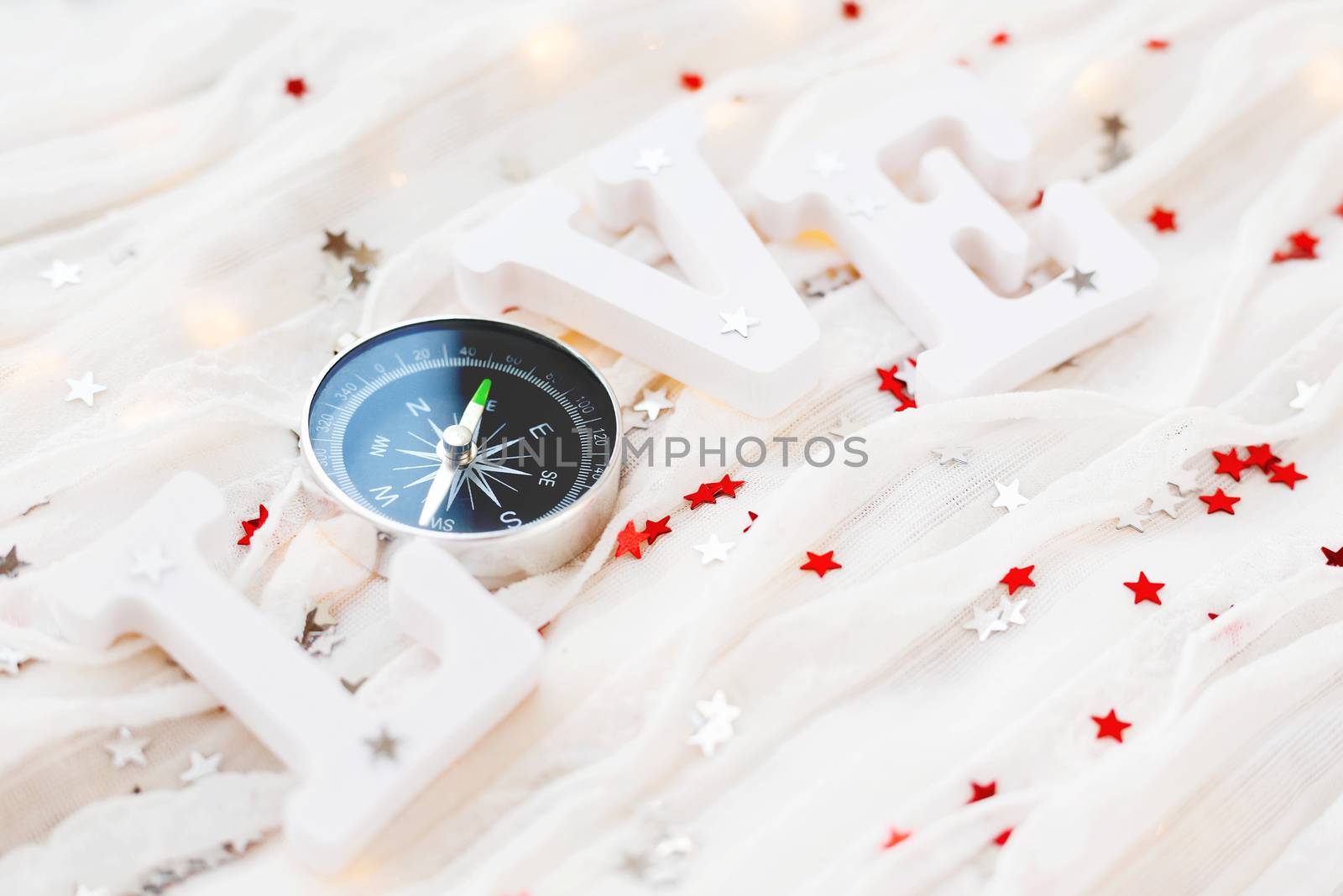 Love background. Travel symbol - compass and confetti on white fabric.