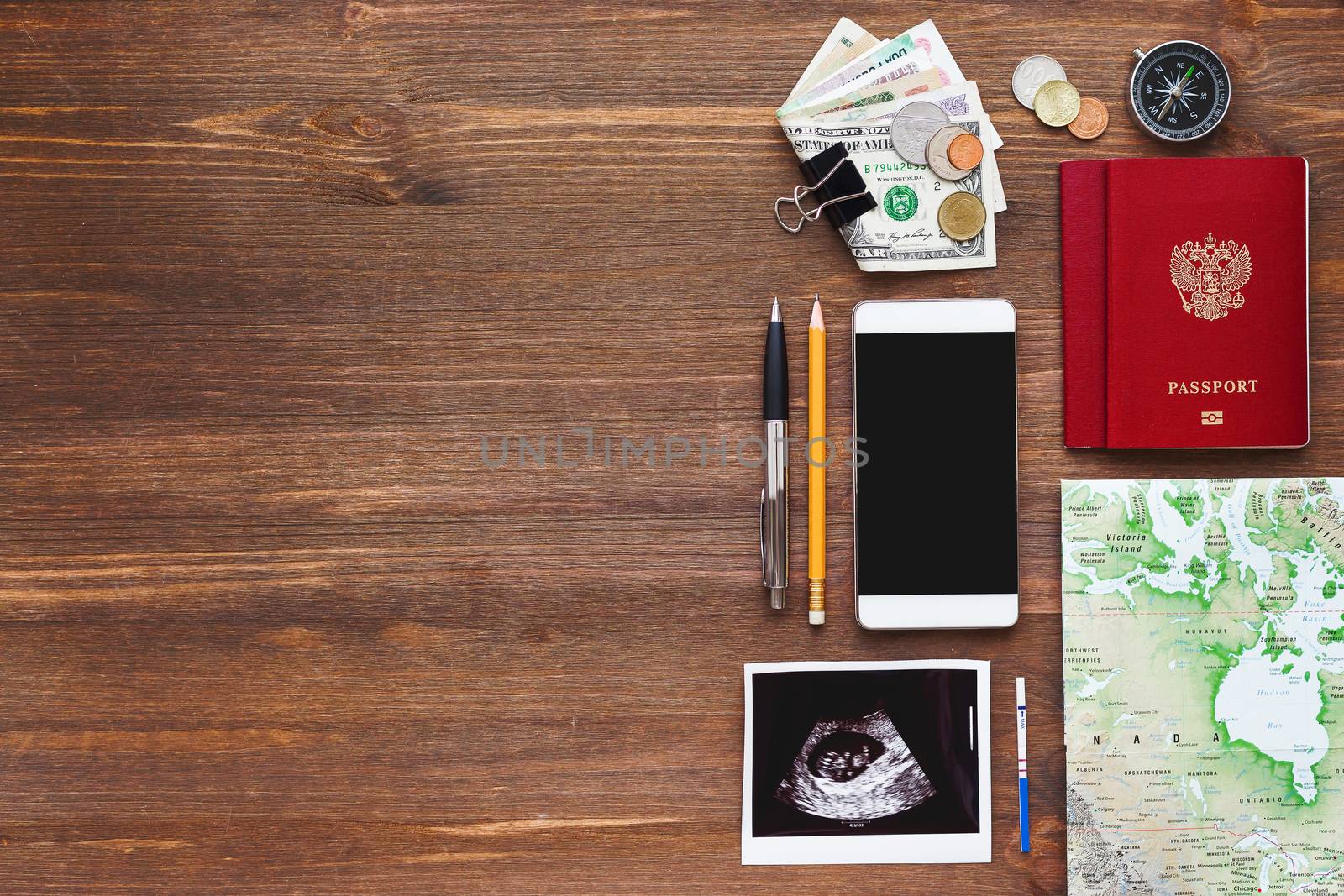 Travel while being pregnant background. Different things you need for journey - smartphone, passport, map, money. Ultrasound photo of baby and positive pregnancy test. Place for text.