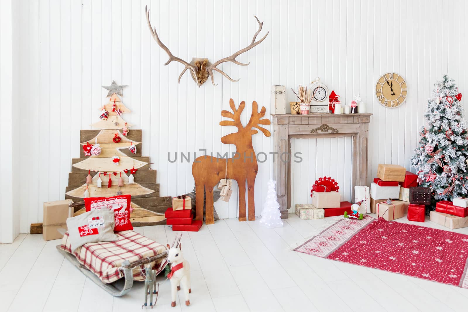 Christmas and New Year details of home interior - wooden deer, mantelpiece with candles, Eve tree and presents.