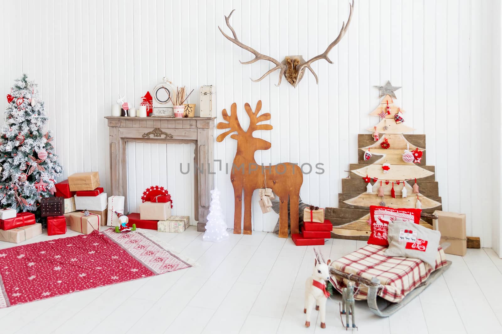Christmas and New Year details of home interior - wooden deer, mantelpiece with candles, Eve tree and presents.