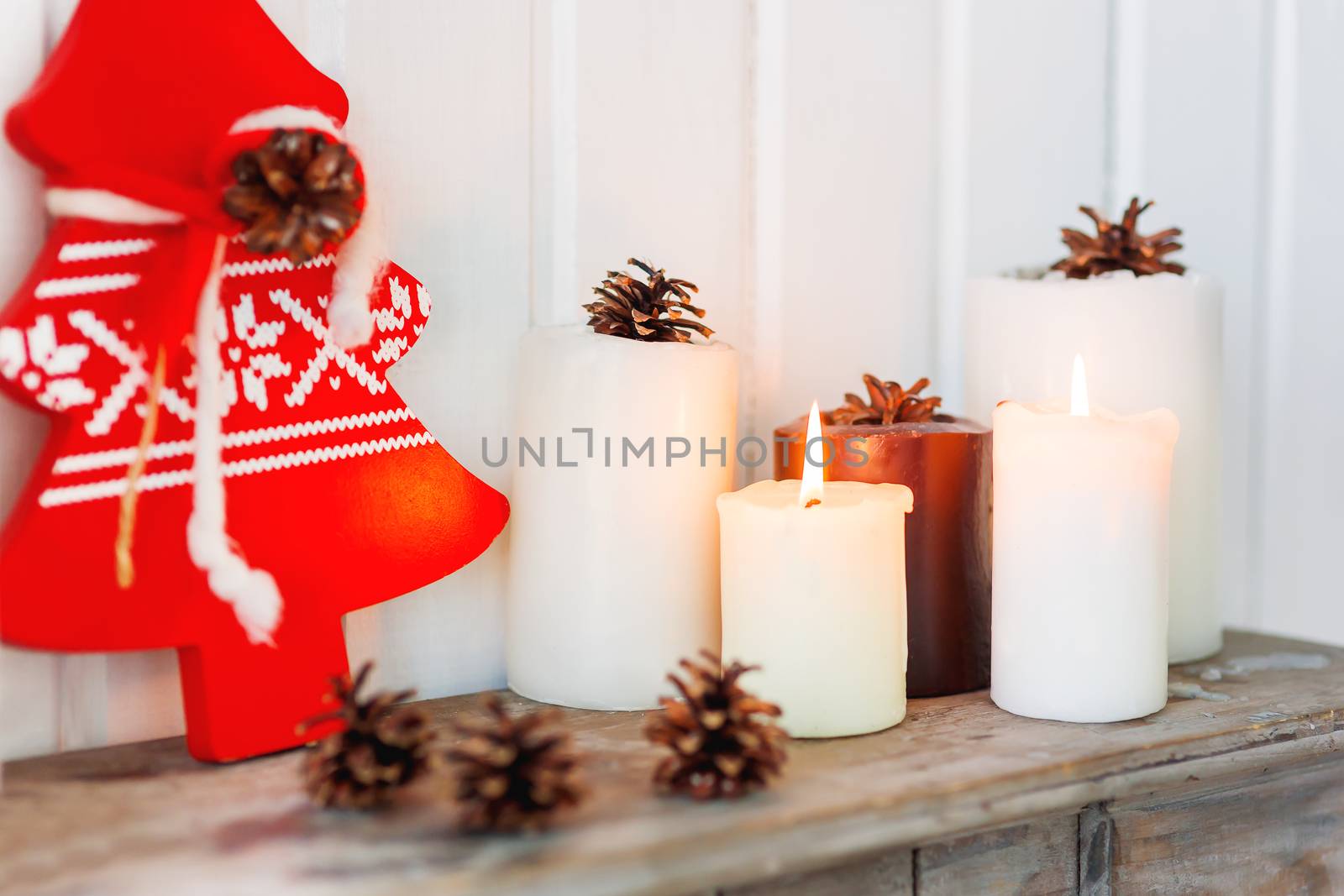 Christmas and New Year background with candles, pine cones and red Eve Tree with nordic pattern. Lovely holiday details of home interior.