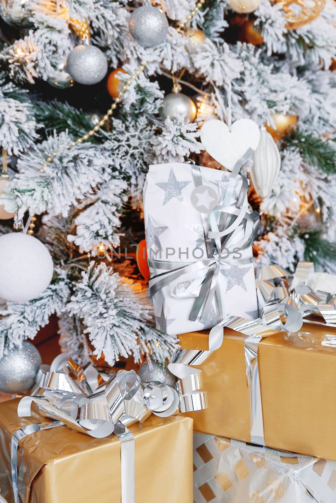 Christmas and New Year background with presents under the Eve Tree. Holiday winter background. Many gifts wrapped in golden and silver paper with bows.