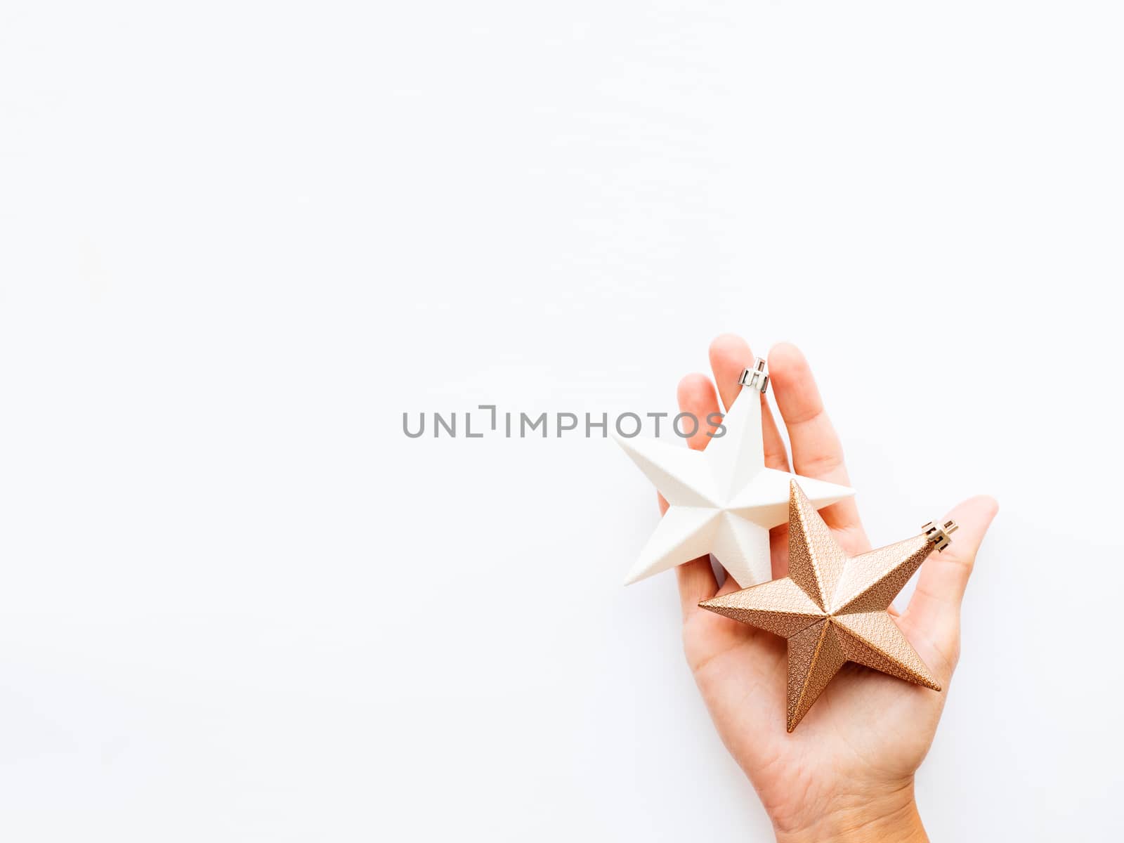 Woman is holding New Year decoration - two stars on white background. Top view on decoration for Christmas tree.