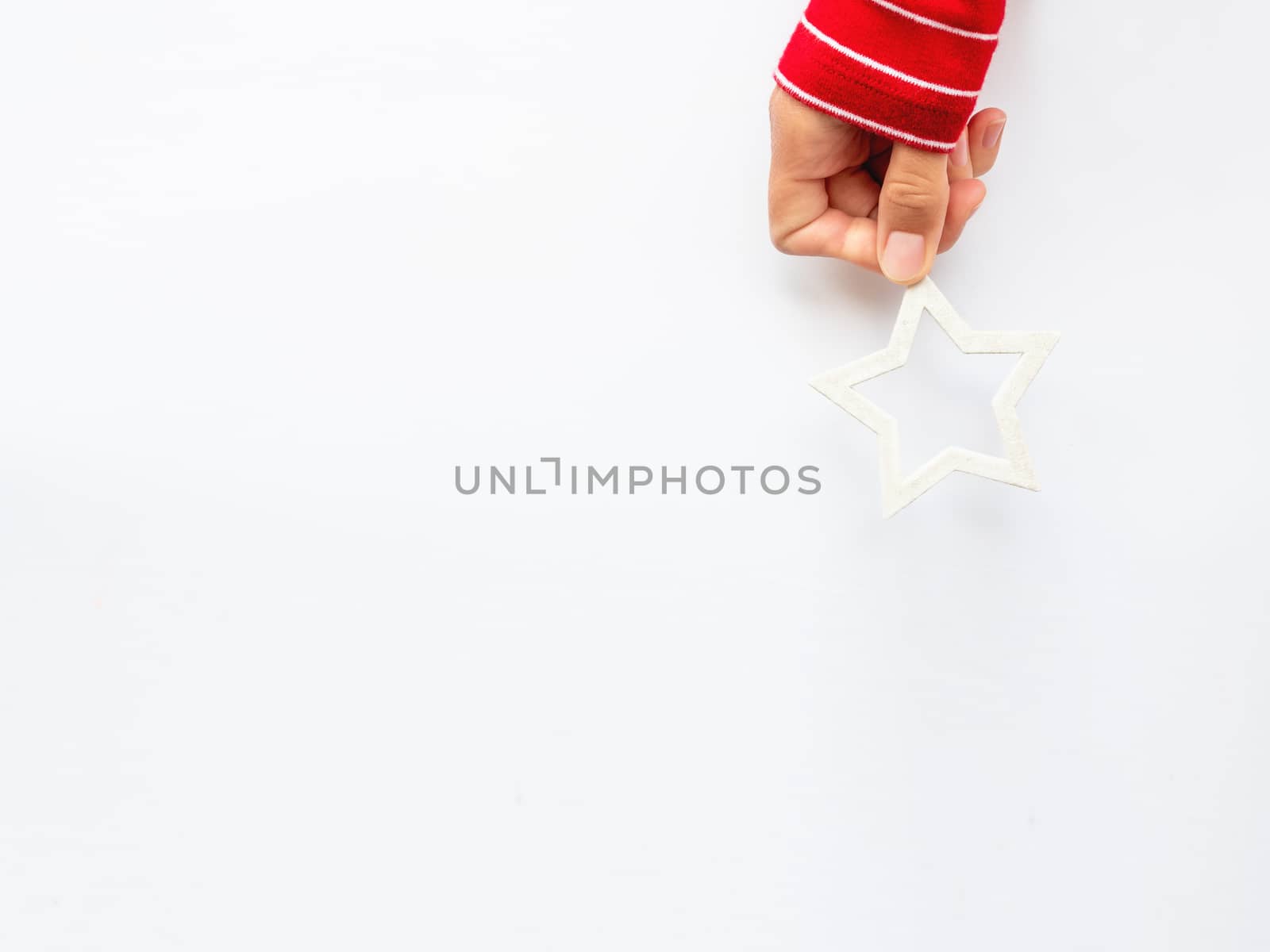 Woman in red sweater is holding New Year decoration - white star on white background. Top view on decoration for Christmas tree.
