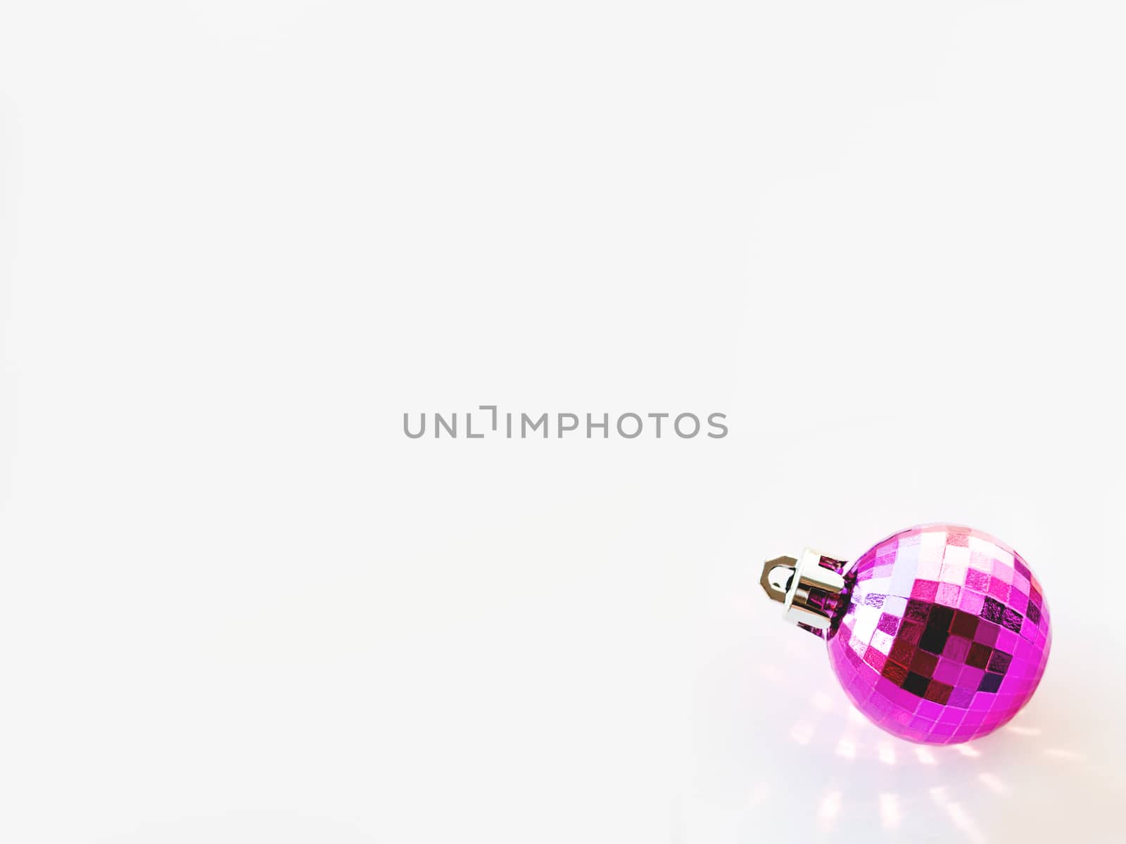 New Year background with magenta ball. Pink reflections, sunbeams on white copy space with decorative ball for Christmas tree.