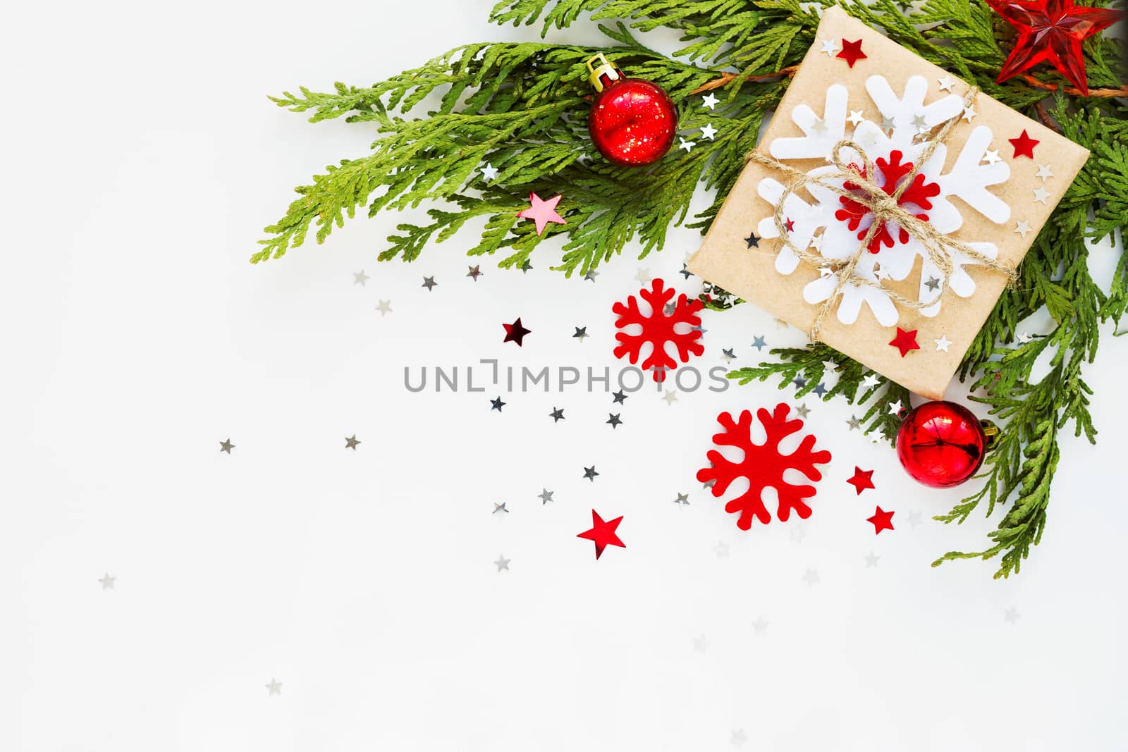 Christmas and New Year background with thuja branch, decorations and present wrapped in craft paper with snowflakes. Flat lay, top view. Place for text.