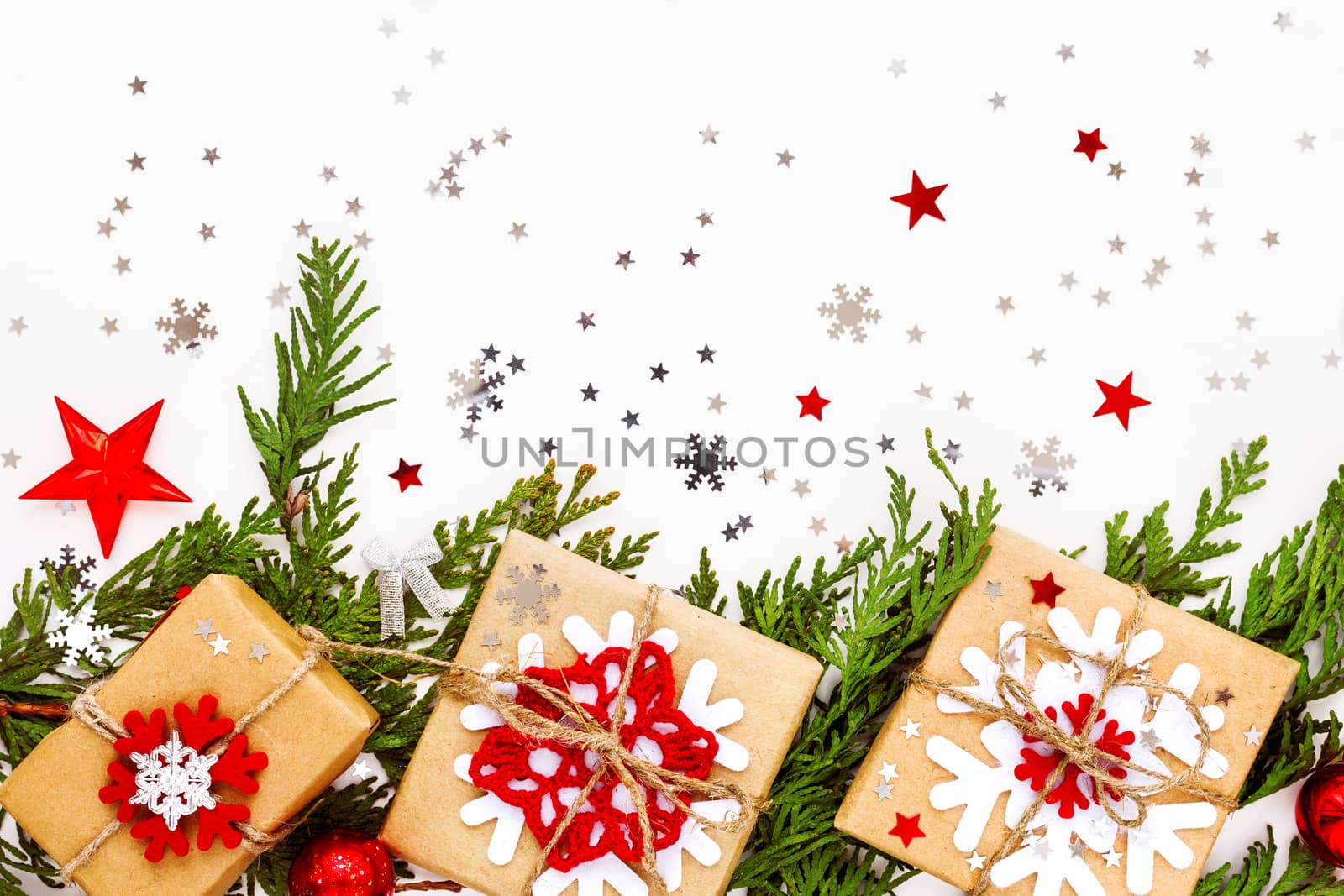 Christmas and New Year background with thuja branch, decorations and presents wrapped in craft paper with snowflakes. Flat lay, top view.