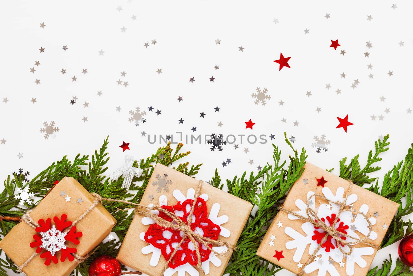 Christmas and New Year background with thuja branch, decorations and presents wrapped in craft paper with snowflakes. Flat lay, top view.