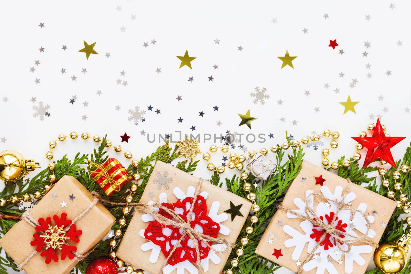 Christmas and New Year background with thuja branch, decorations and presents wrapped in craft paper with snowflakes. Flat lay, top view.