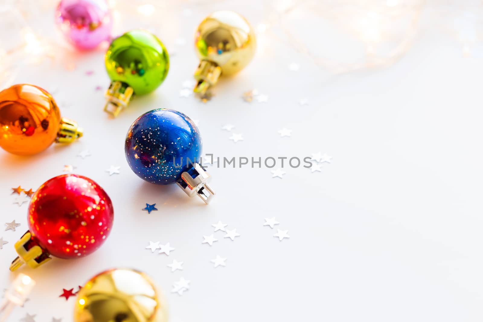 Christmas and New Year background with colorful decorative balls for Christmas tree with light bulbs and confetti. Place for text.