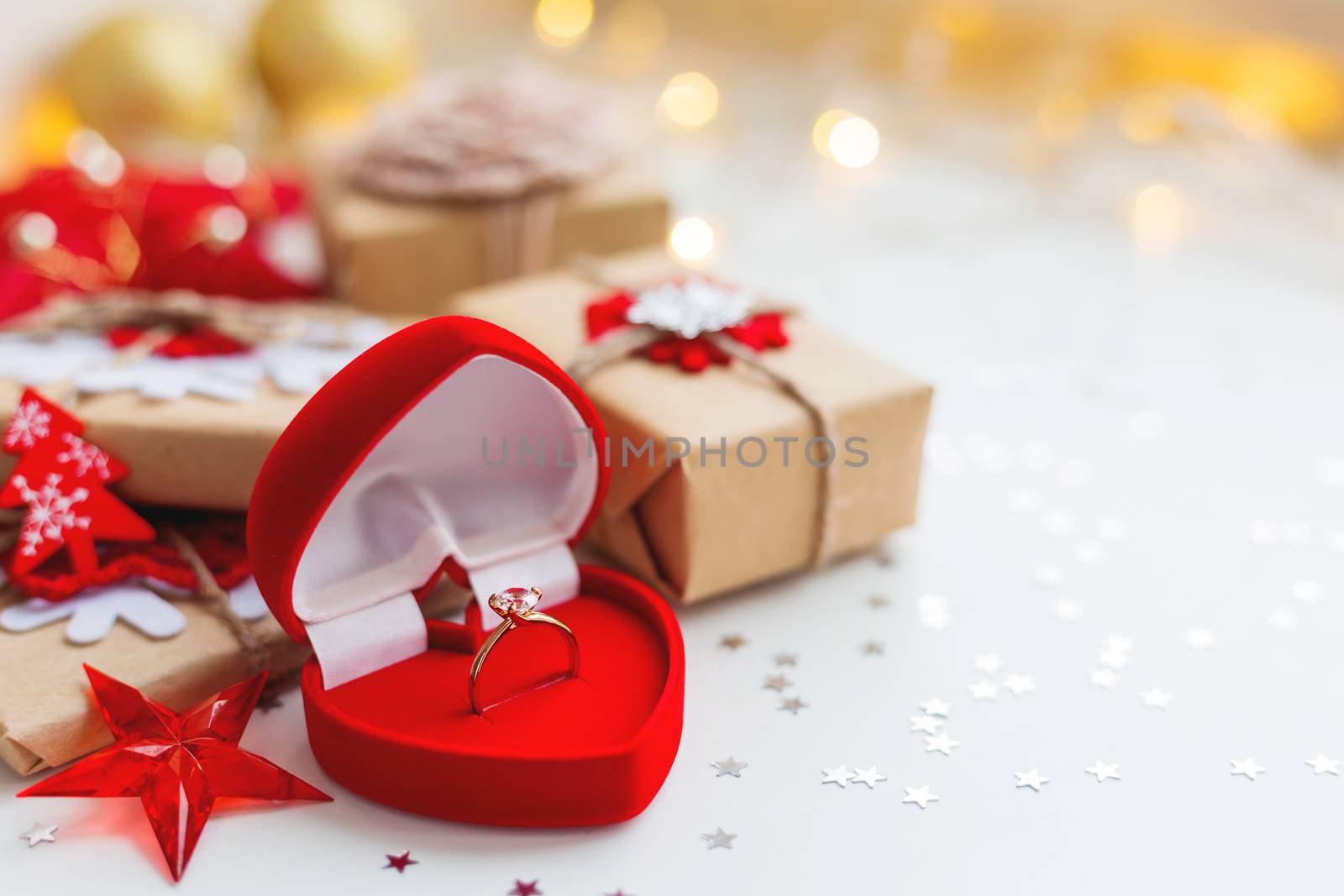 Christmas and New Year background with engagement ring and presents, decorations for Christmas tree. Holiday background with stars confetti and light bulbs. Place for text.