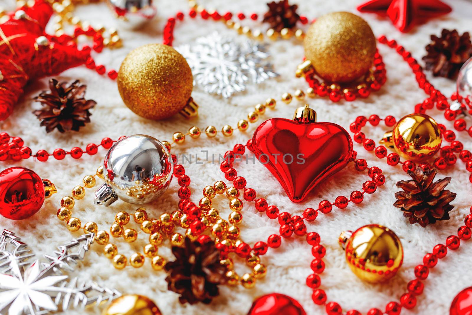 Christmas and New Year background with decorations - balls, stars, silver sparkling snowflakes, heart on knitted fabric with decorative pattern.