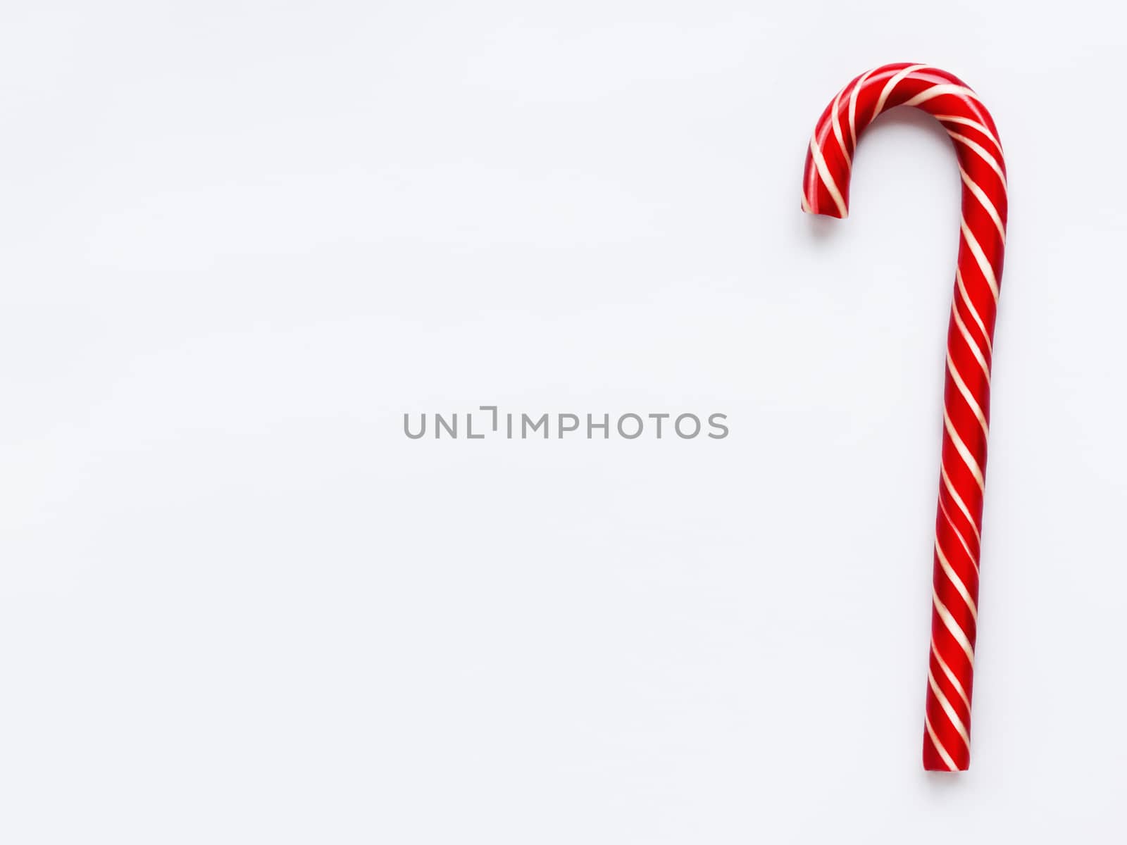 Christmas candy cone on white background. Colorful holiday sweet lollipop with copy space. Dessert wtih red and white stripes.