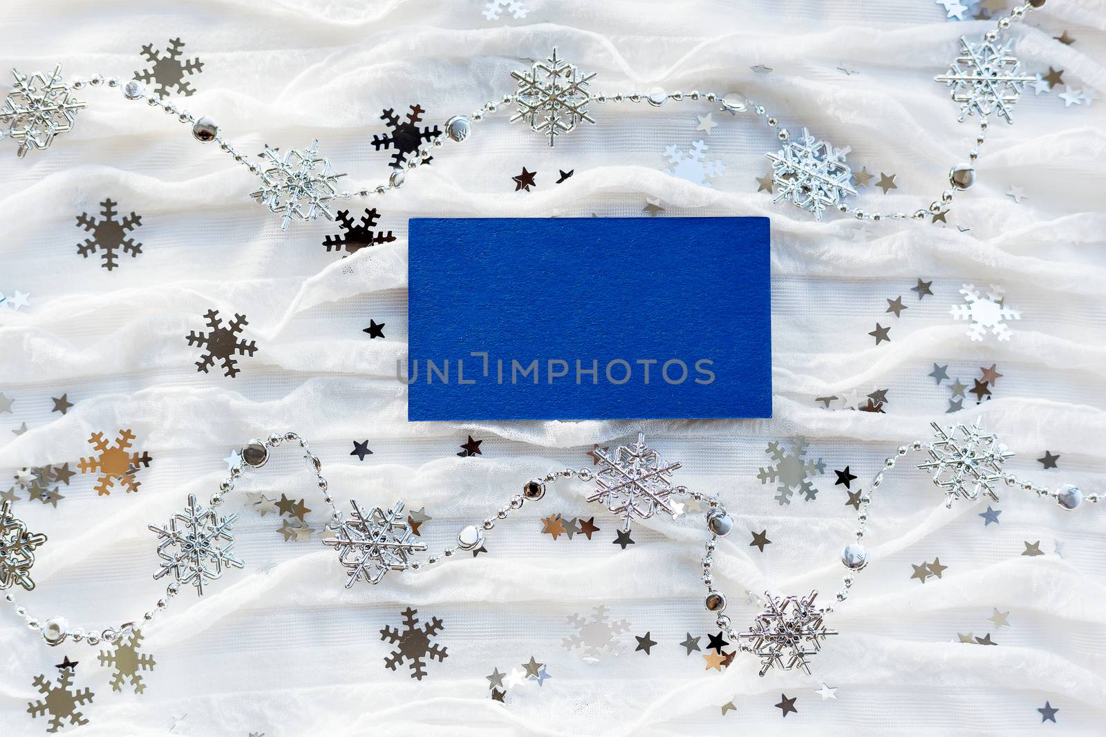 Winter background with decorative sparkling snowflakes and empty piece of blue paper for your text.