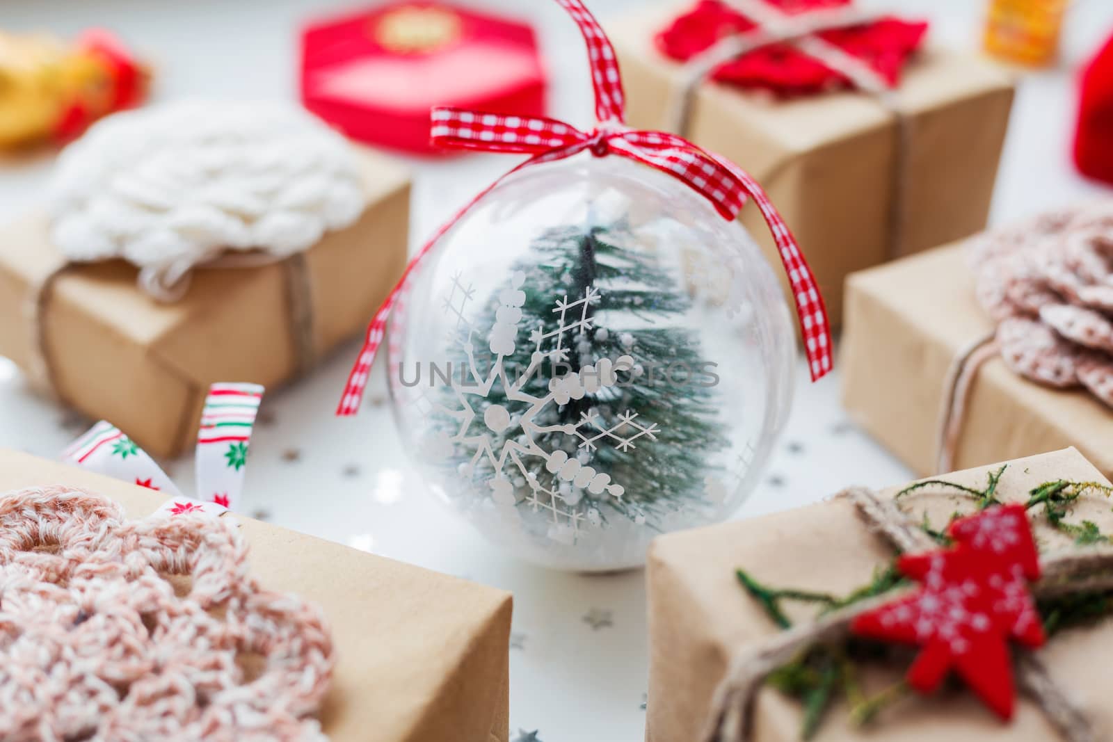 Christmas and New Year background with presents, decorations and transparent decorative ball with fir tree inside.